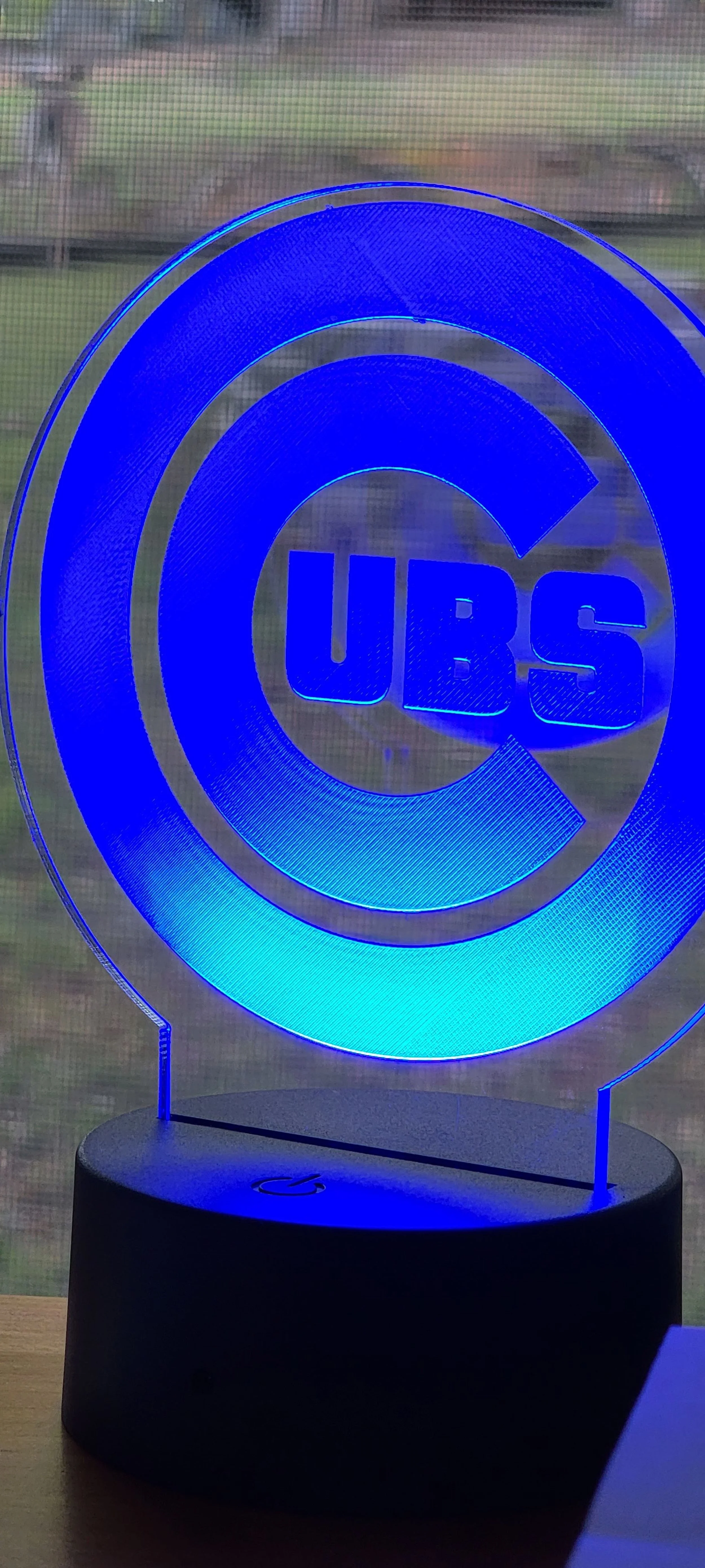 Blue LED Cubs logo on a black base, placed against a window.