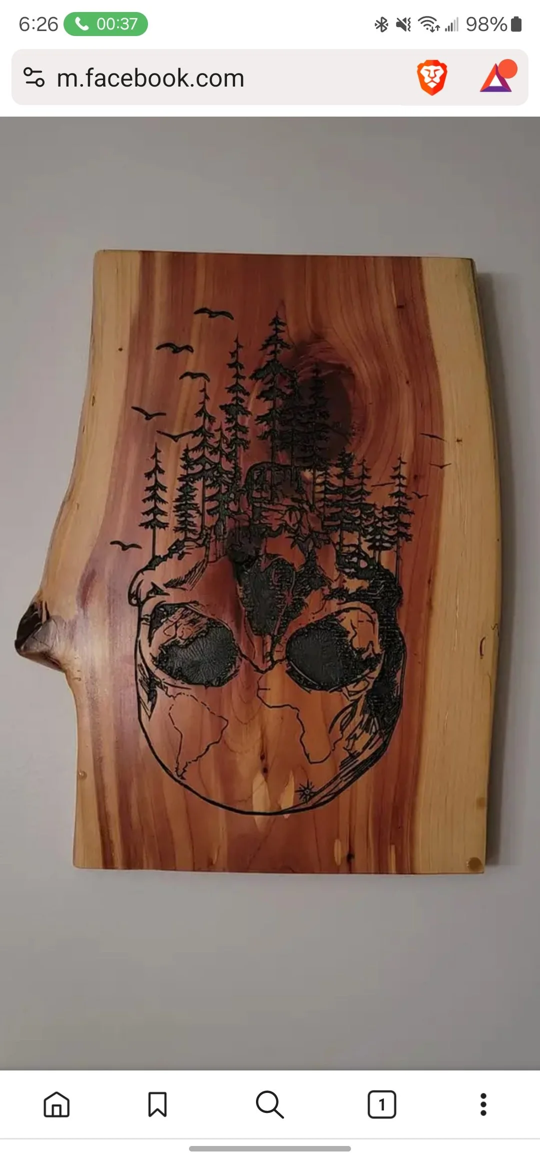 Wooden art piece with a skull design, featuring trees and birds carved into it.