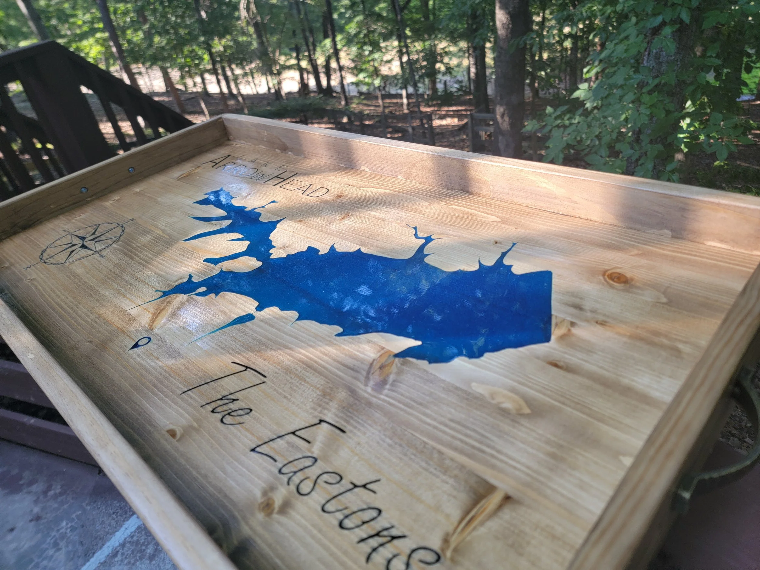 Wooden tray featuring map of Arrowhead Lake with blue resin inlay and compass design, "The Eastons" text, surrounded by trees.