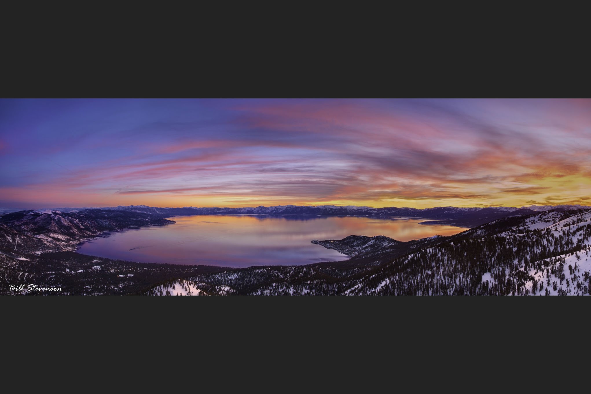 A panorama photo of sunset over Lake Tahoe in winter.