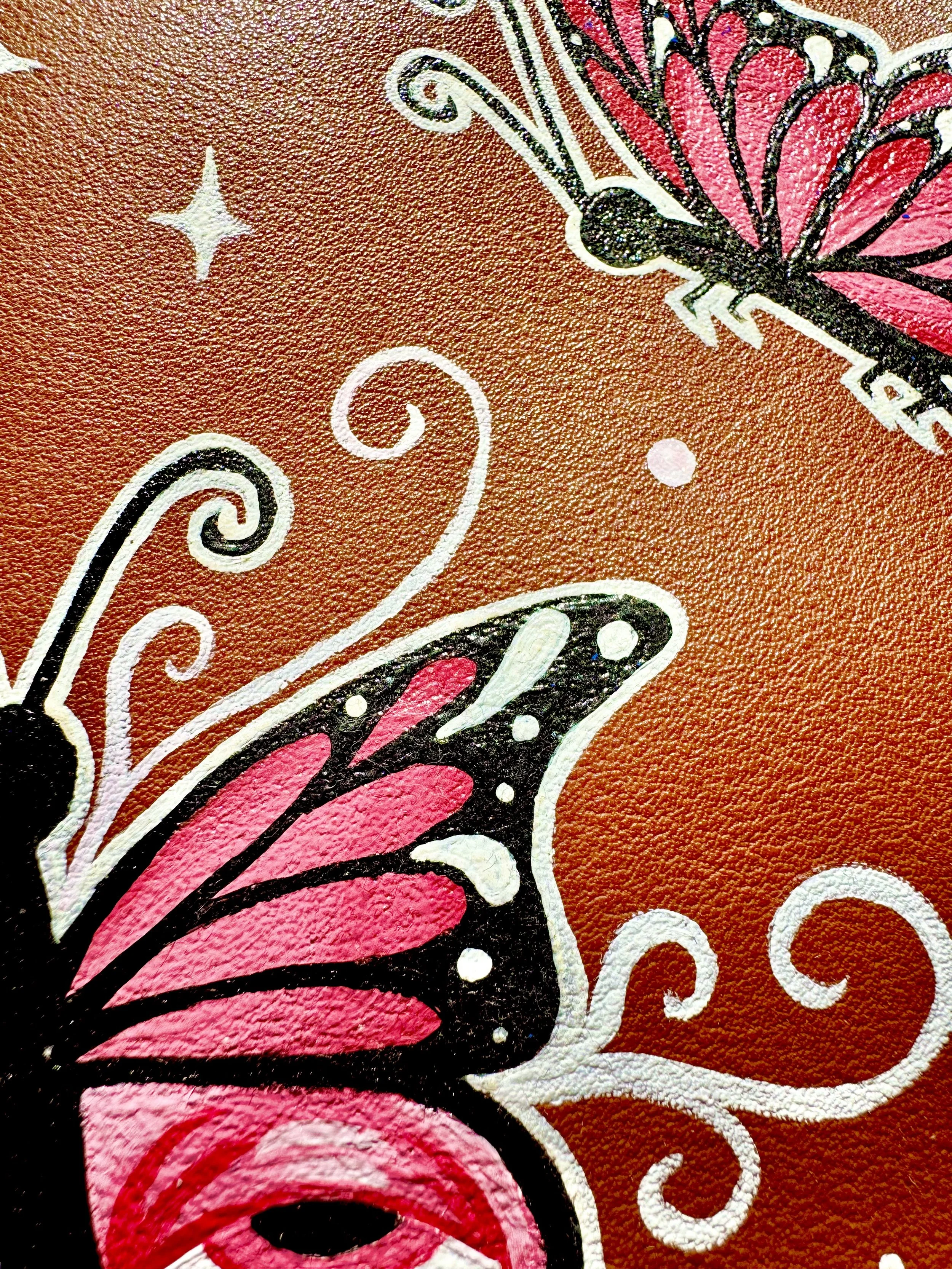Close-up of a colorful butterfly and floral design on textured orange background.