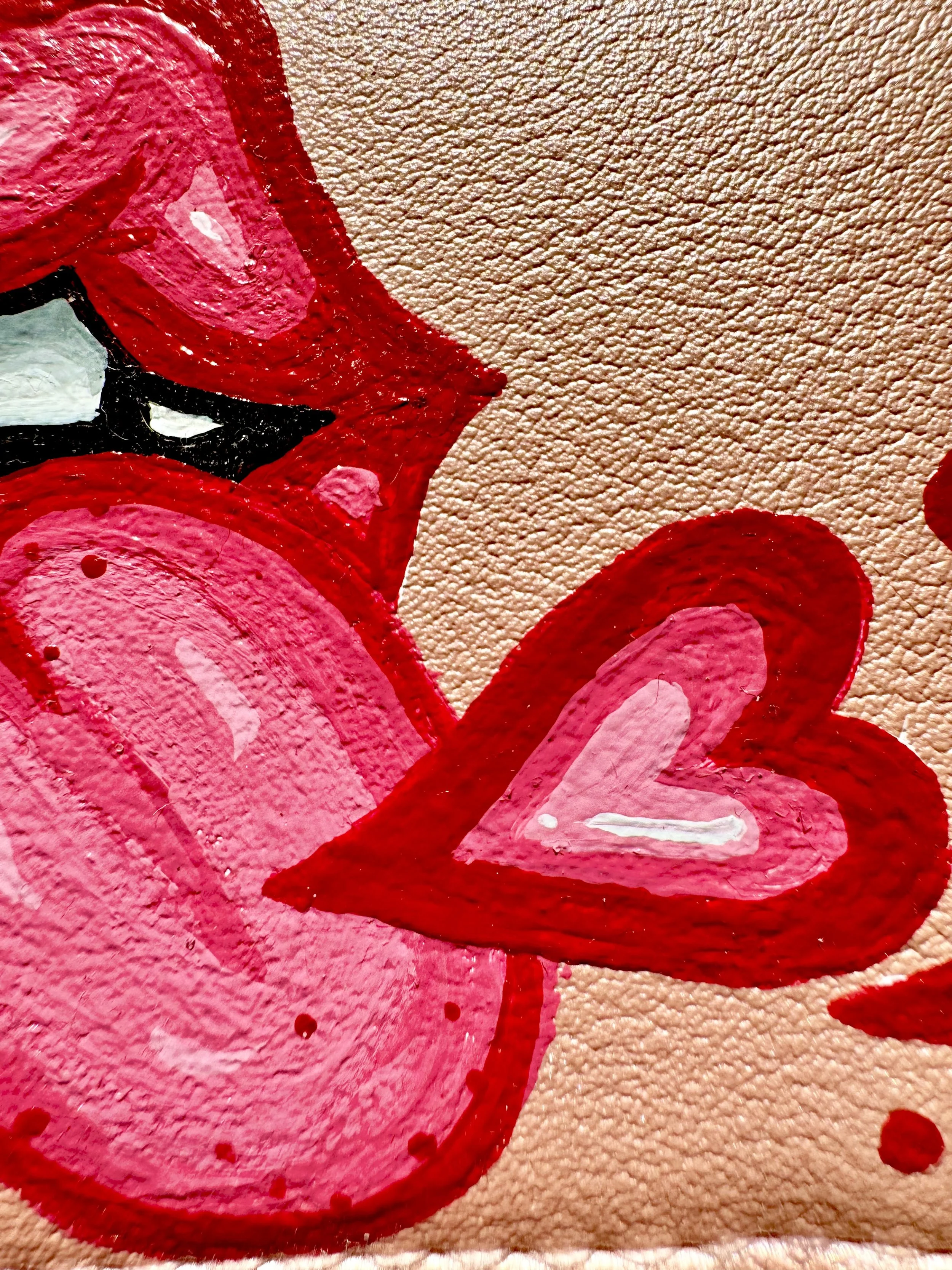 Close-up of a painted mural featuring pink and red hearts on a textured wall.