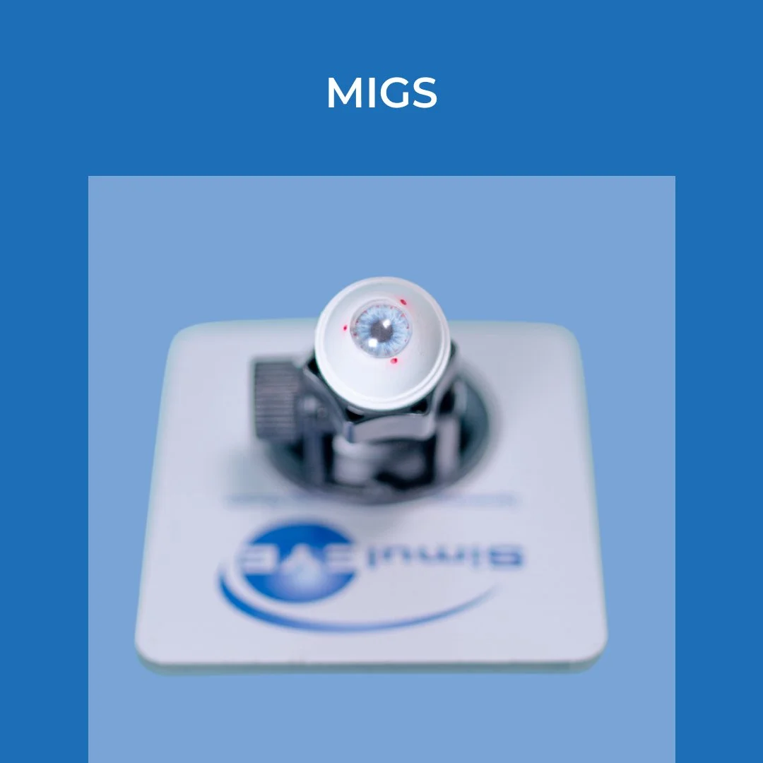 Close-up view of a medical device with a lens and red laser dots, labeled 'MIGS', placed on a white surface with a blue logo.