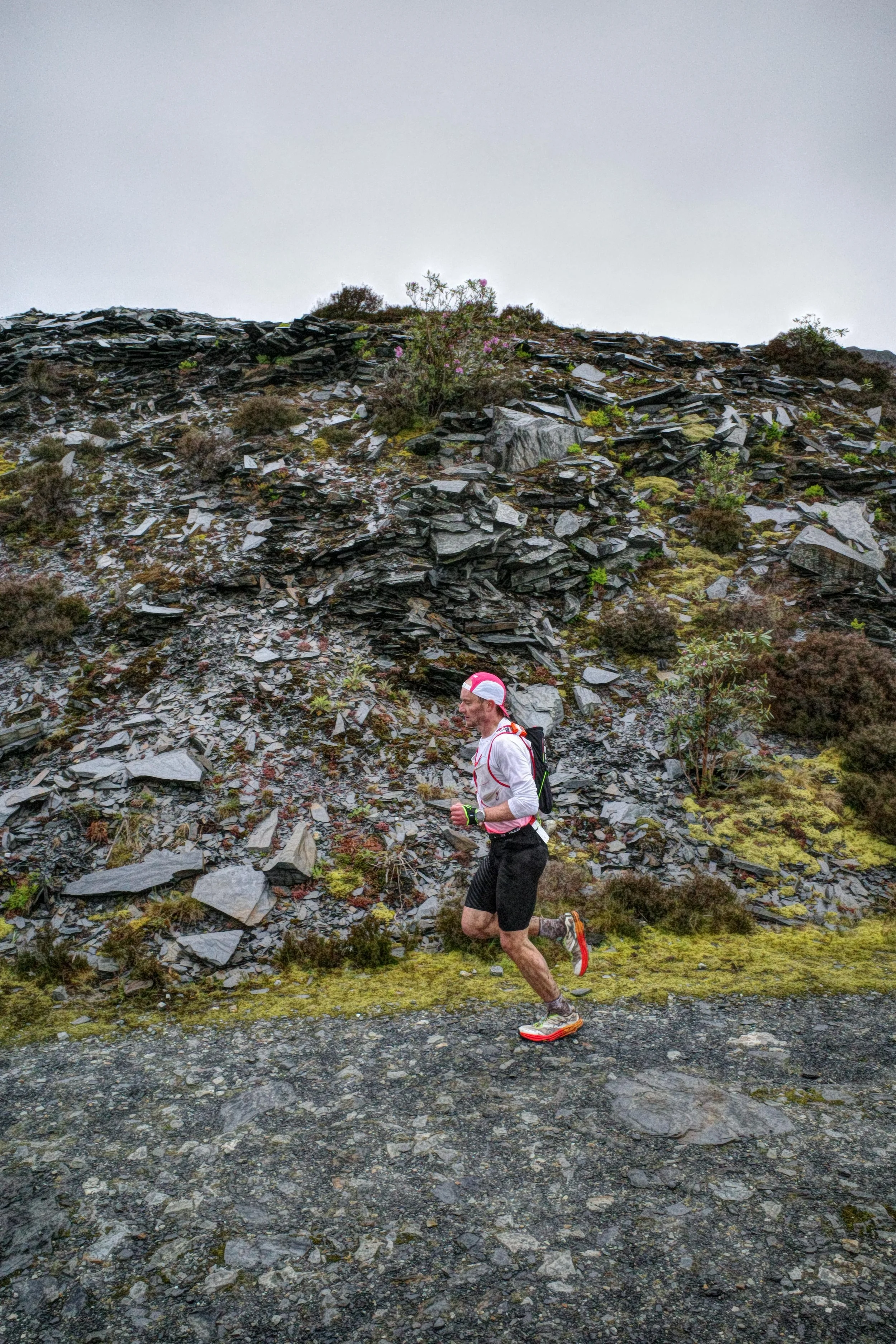 Trail runner on Welsh trails, surrounded by slate-filled hills
