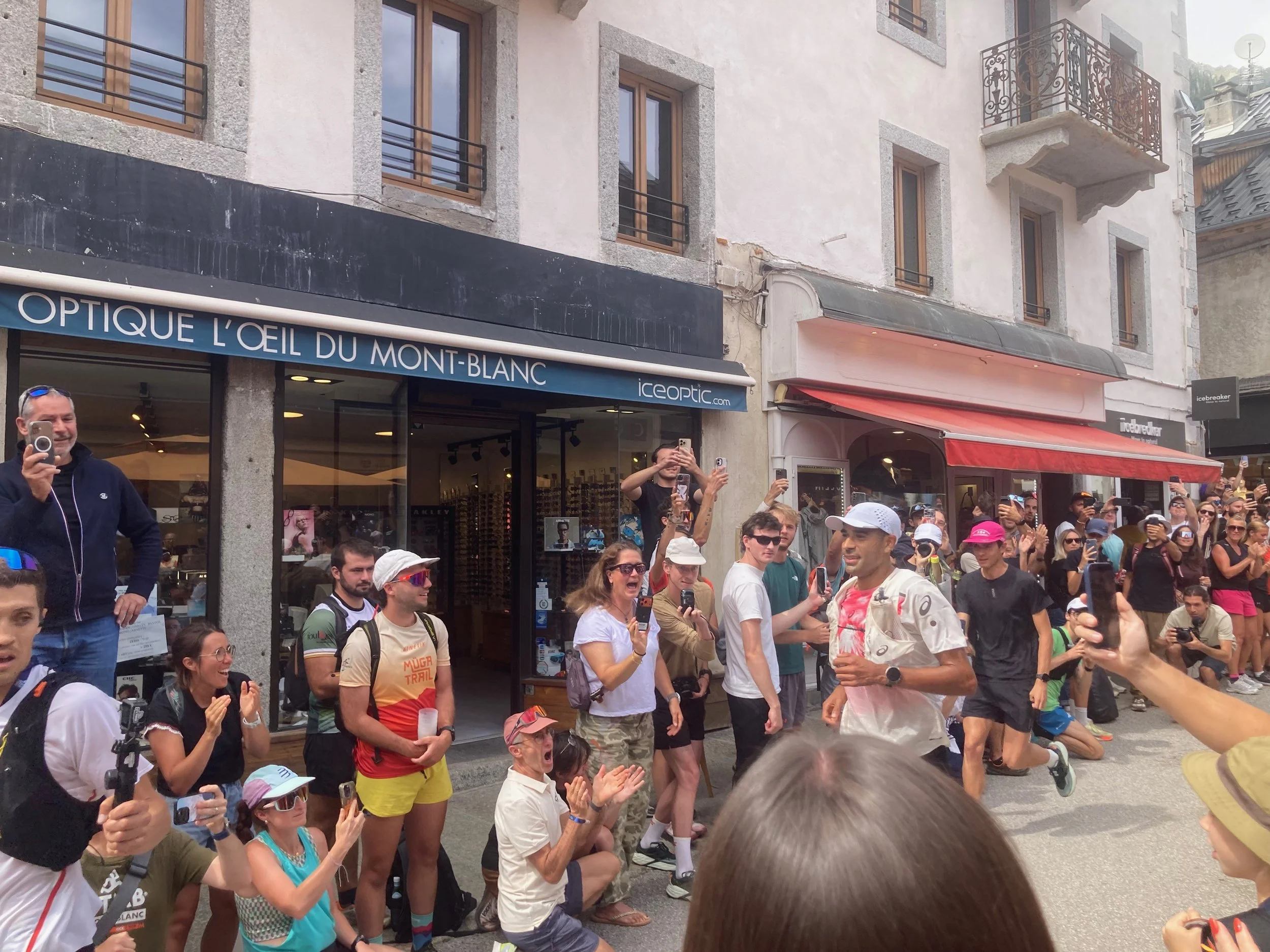 Trail runner passing through a busy city surrounded by spectators