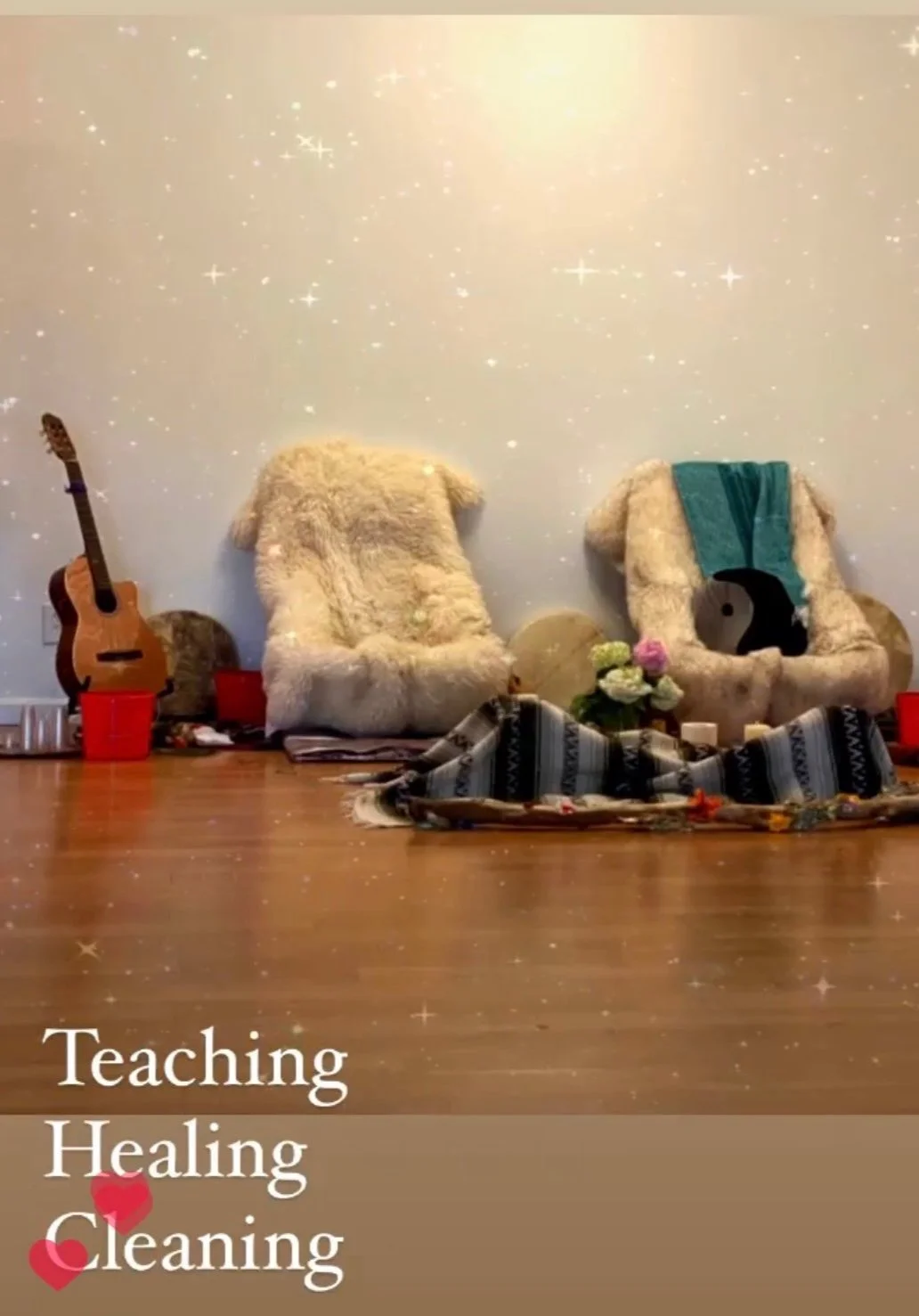 Two fuzzy chairs with a guitar and drums nearby, decorated space featuring blankets and flowers, with text 'Teaching Healing Cleaning' and heart icons.