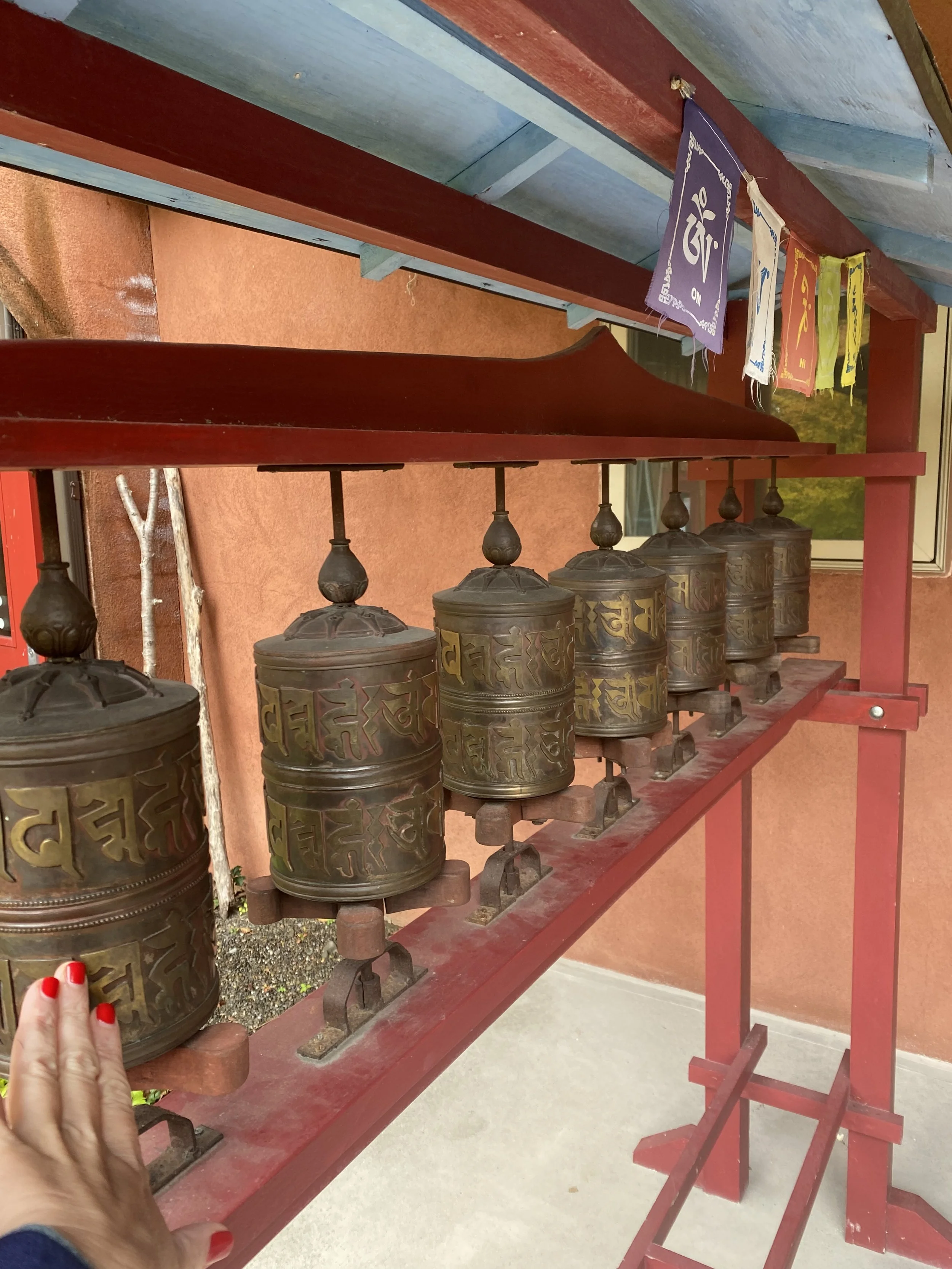 Tibetan prayer wheels with inscriptions and a row of colorful prayer flags above.