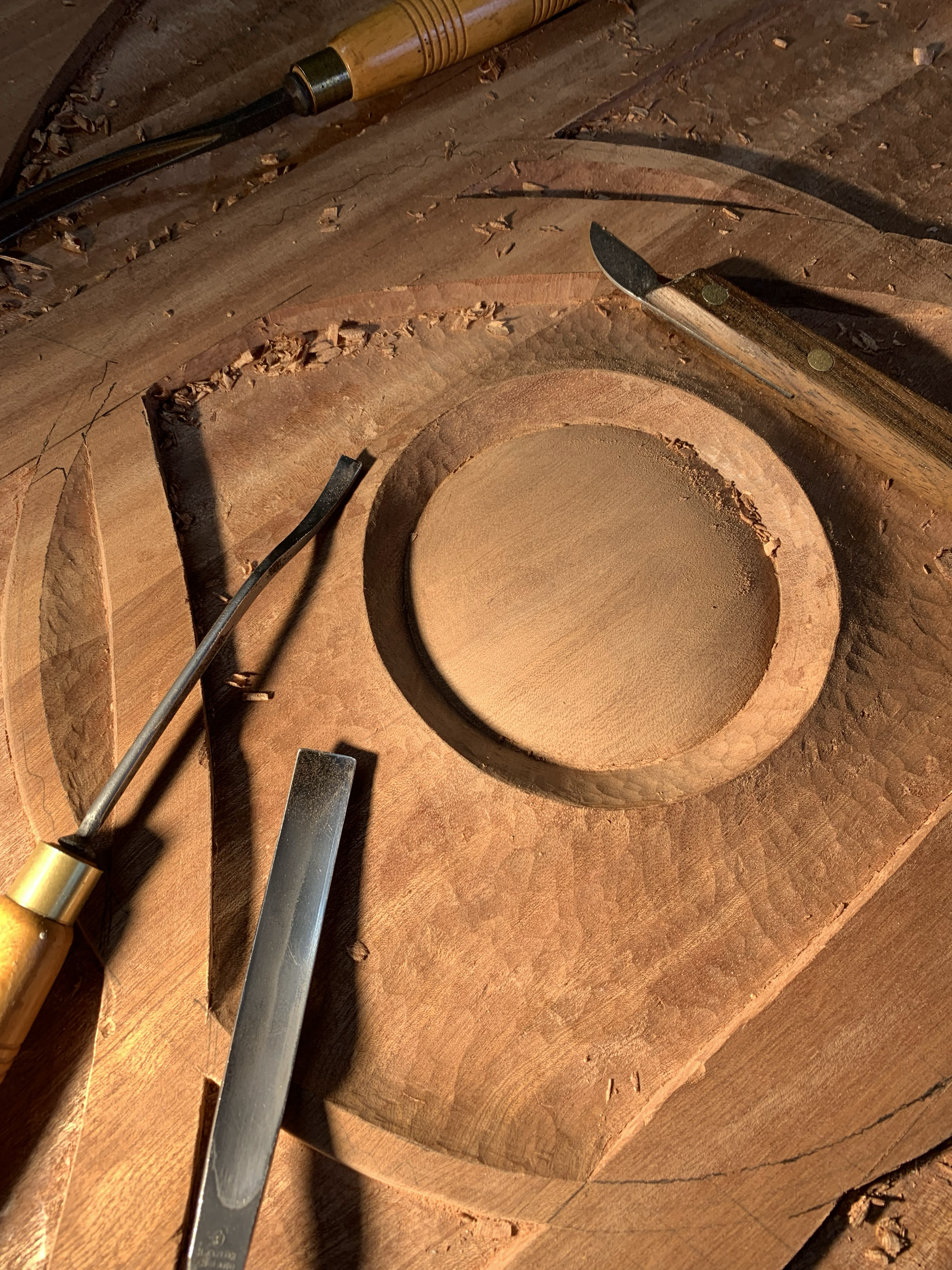 Hand carving in progress in the studio using traditional woodworking tools.