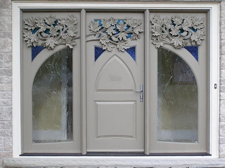 Front door with decorative carved wooden leaves and stained glass accents