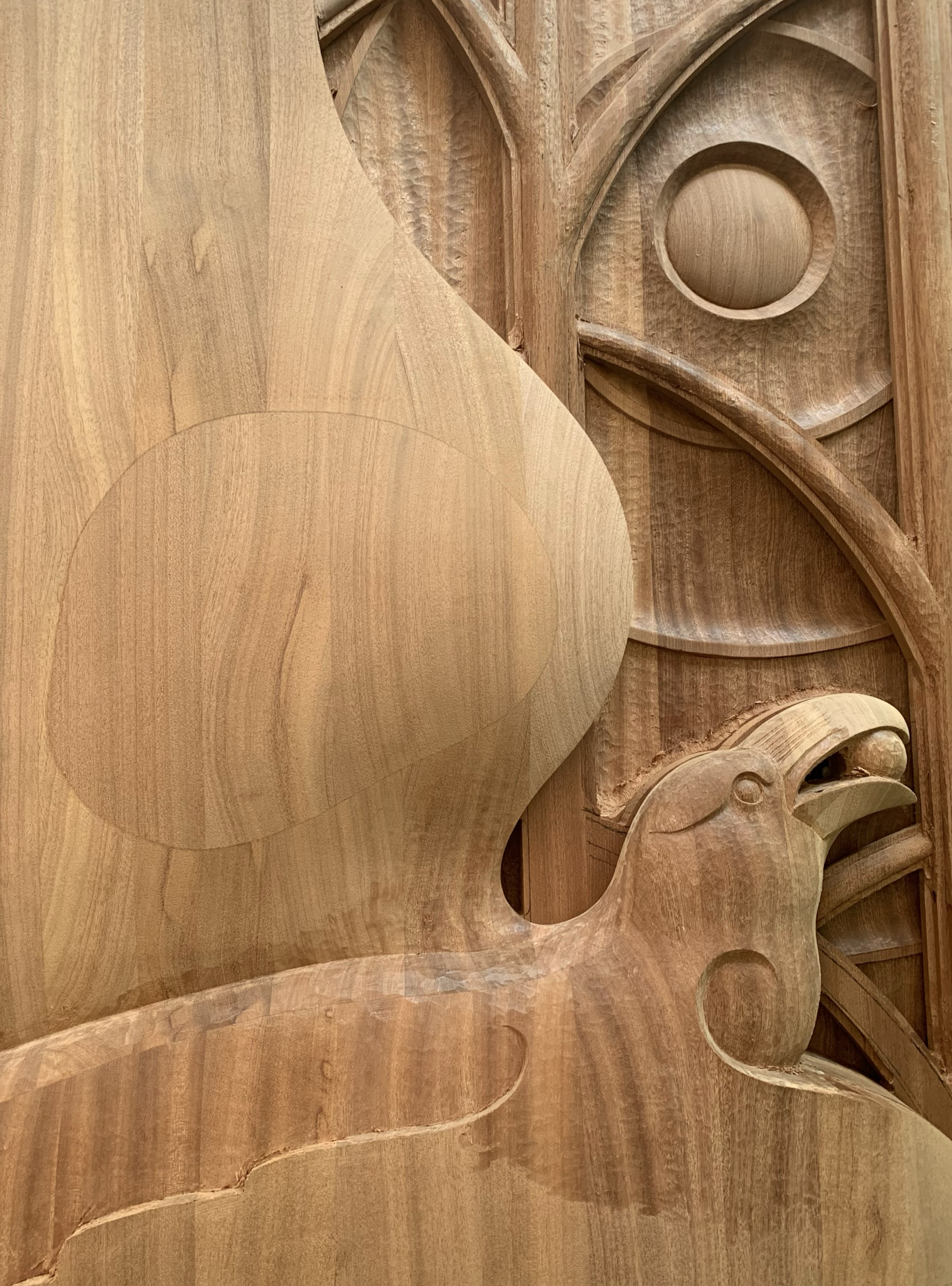 Carved raven detail in a mahogany entrance door with stained glass elements.