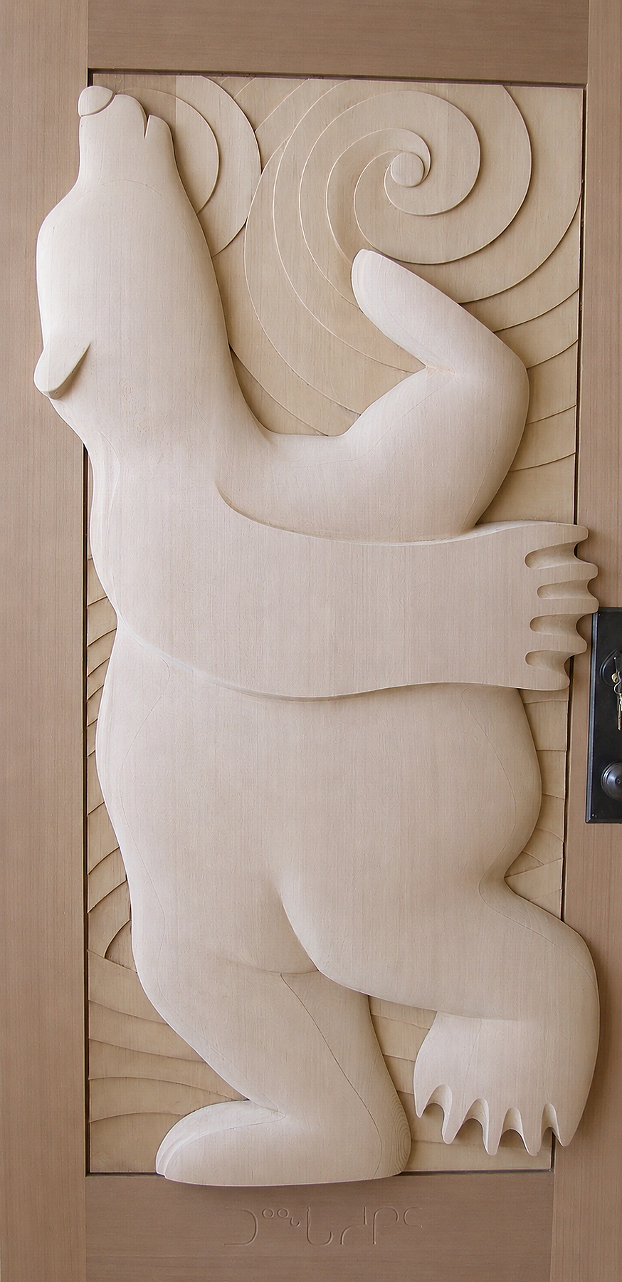 Carved cedar bear figure surrounded by flowing organic forms.
