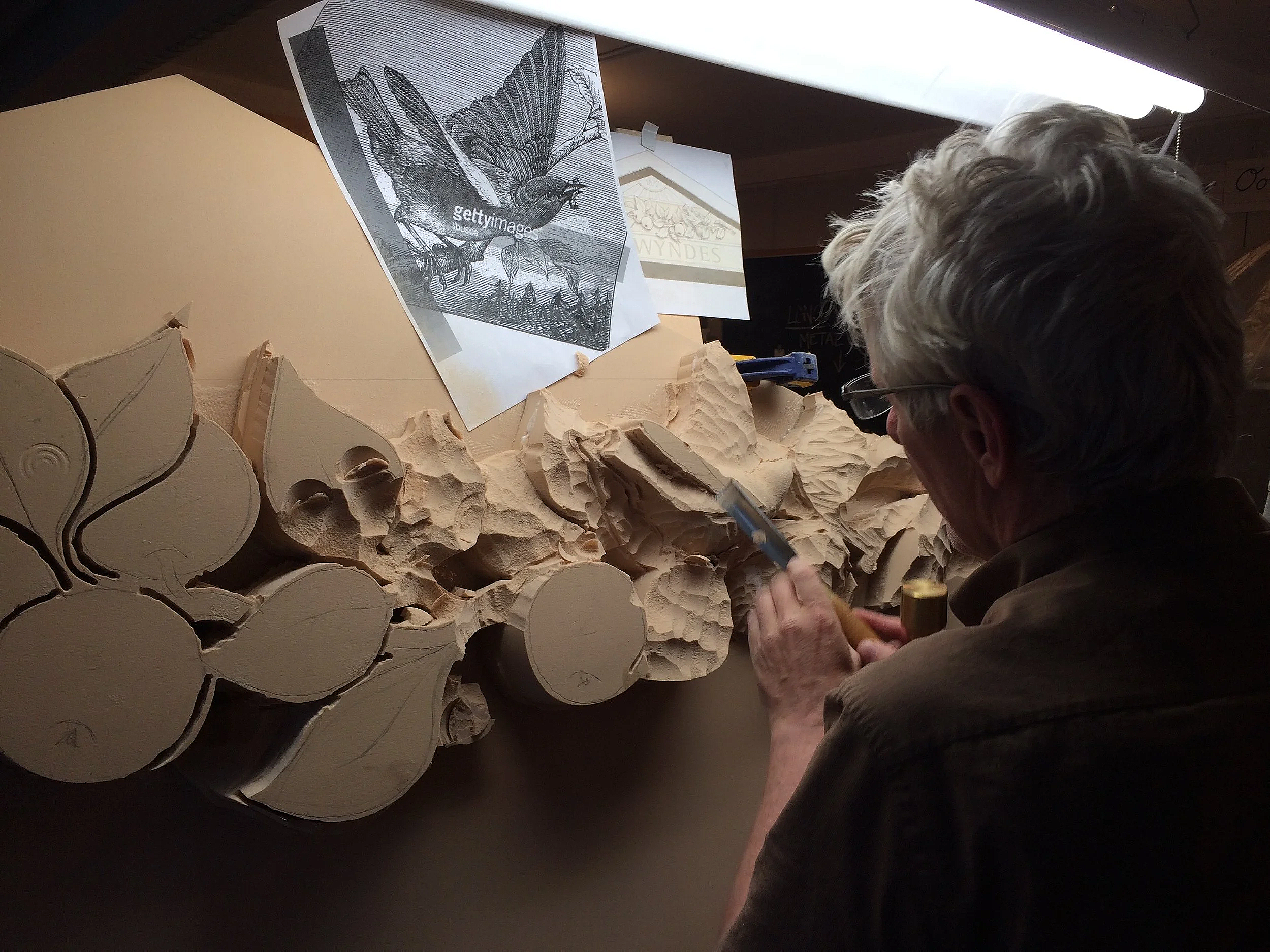 Hand carving in progress in the studio using traditional woodworking tools.