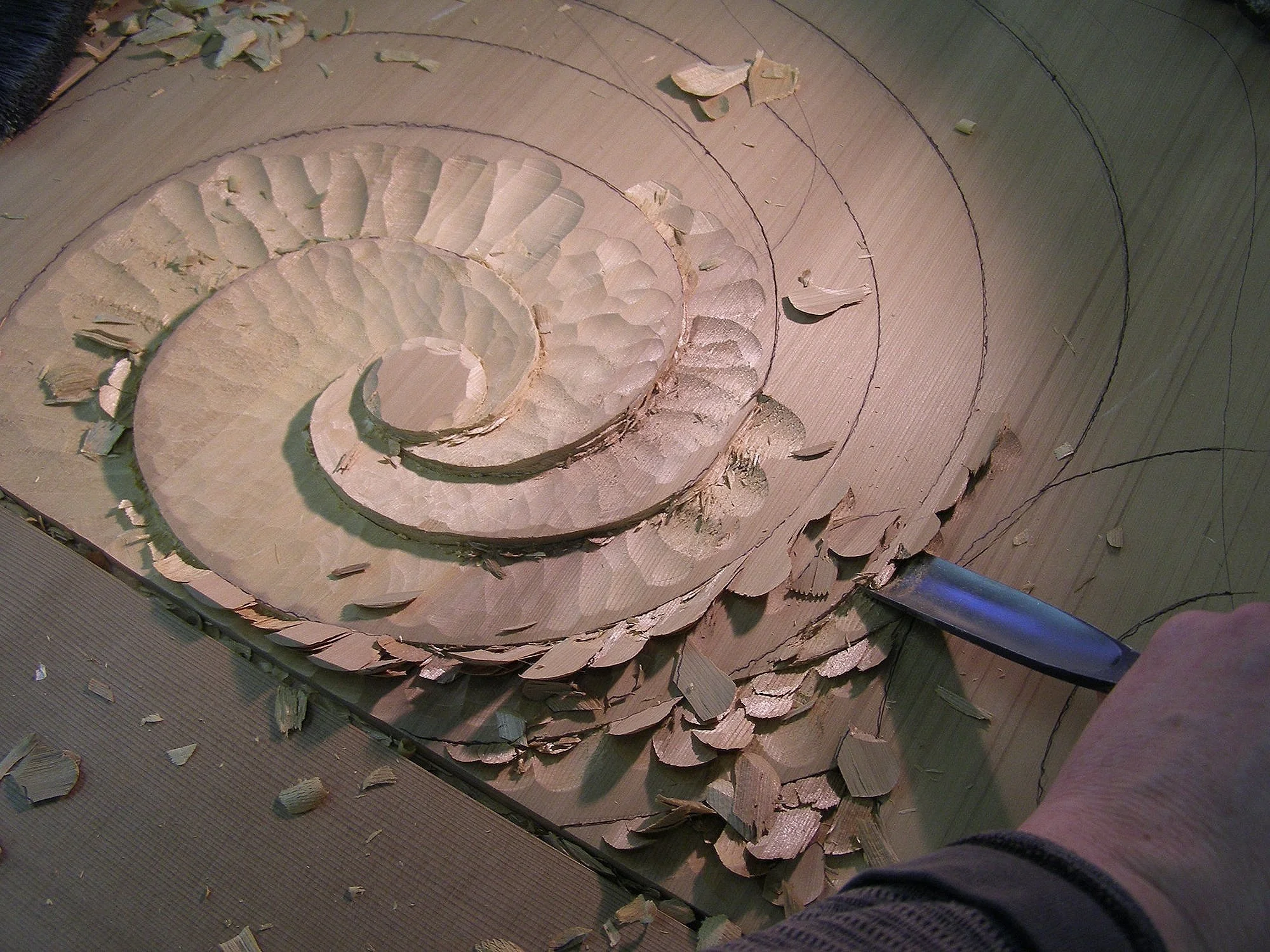 Hand carving in progress in the studio using traditional woodworking tools.