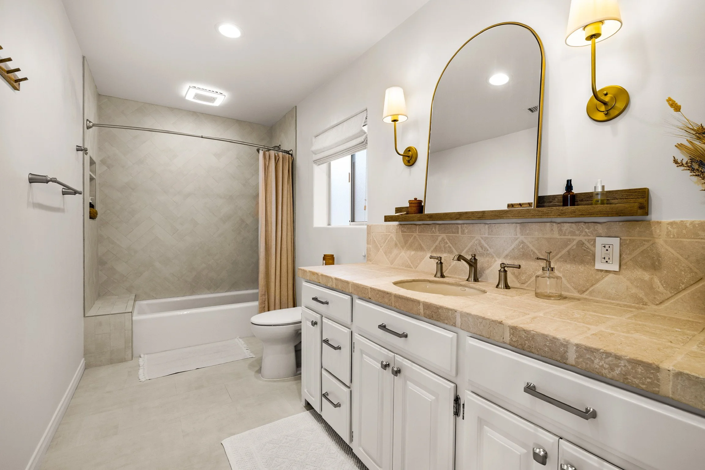Herringbone ceramic tile shower, new brass wall sconces and floating mirror with a natural palette creates the ease that Santa Barbara has to offer. 