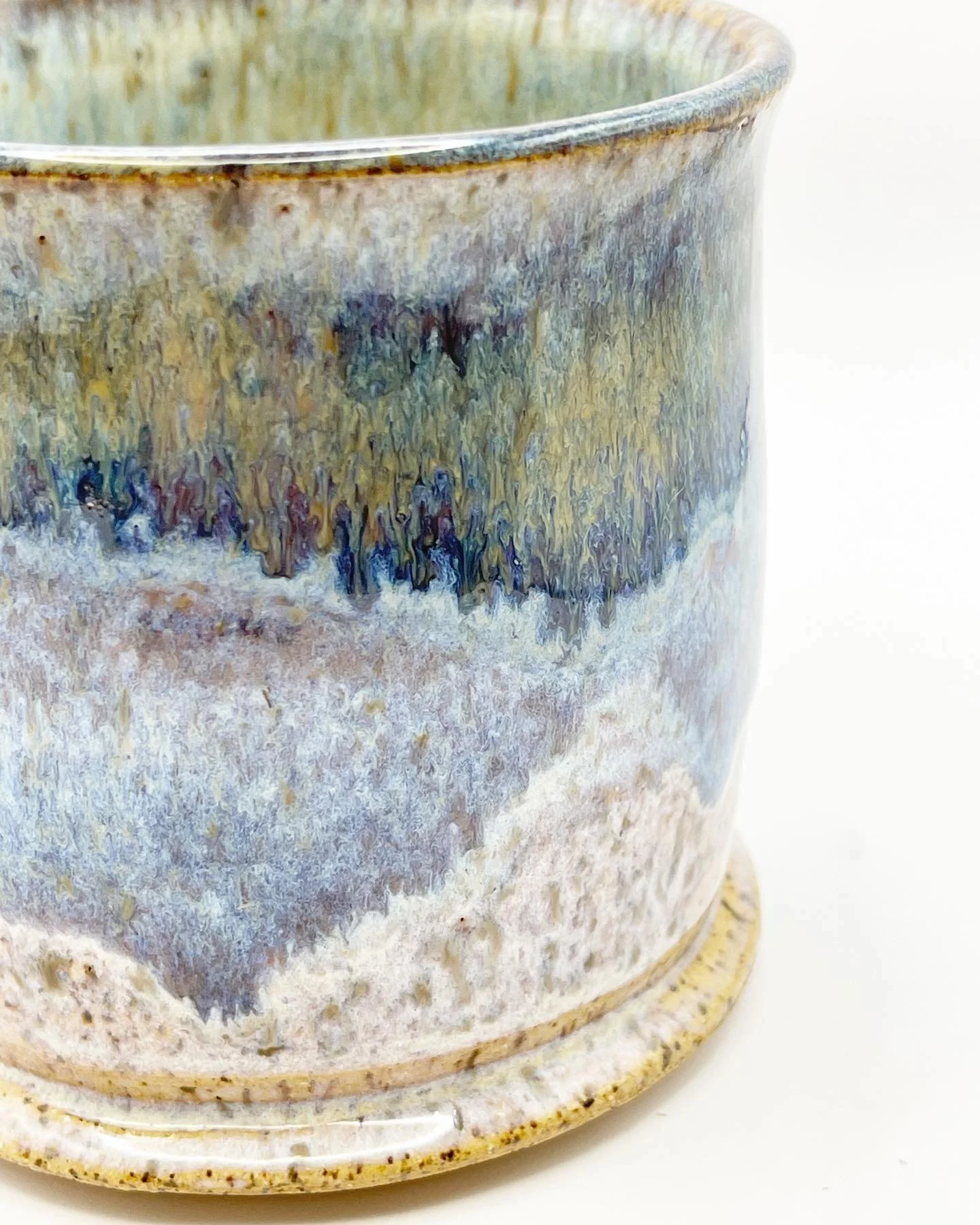 Close-up of a textured ceramic mug with a glazy finish in shades of brown, blue, and cream.