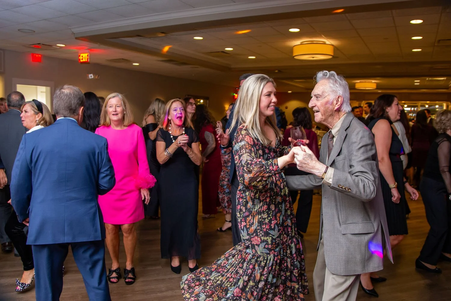 People dancing and socializing at a lively party or celebration in an indoor event space.