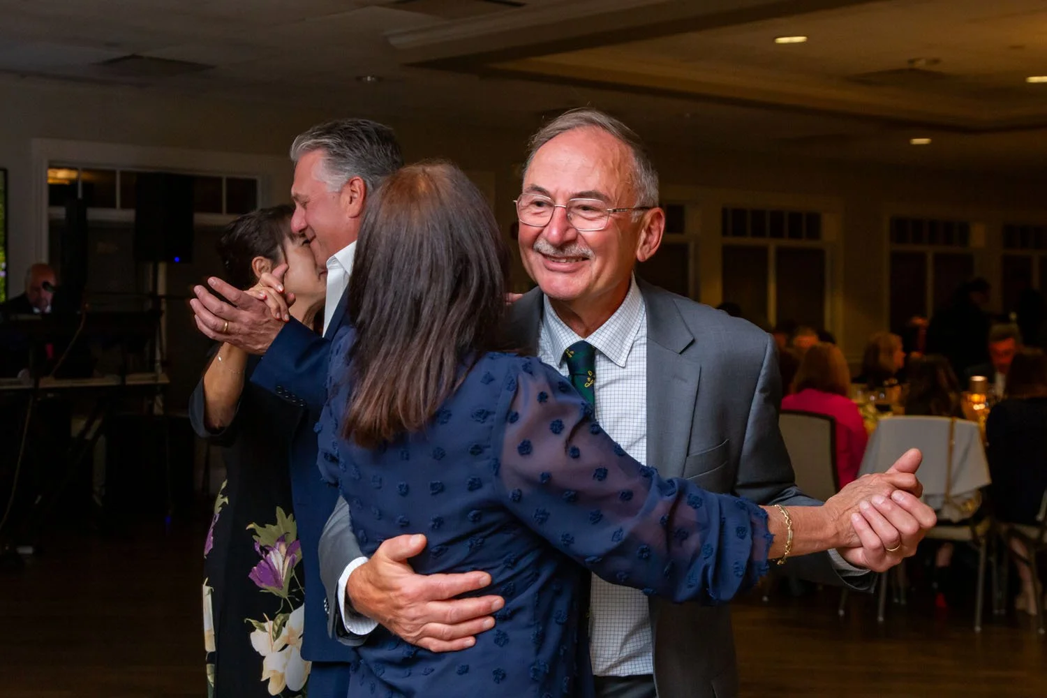 People dancing and socializing at a formal event or celebration in an indoor venue.