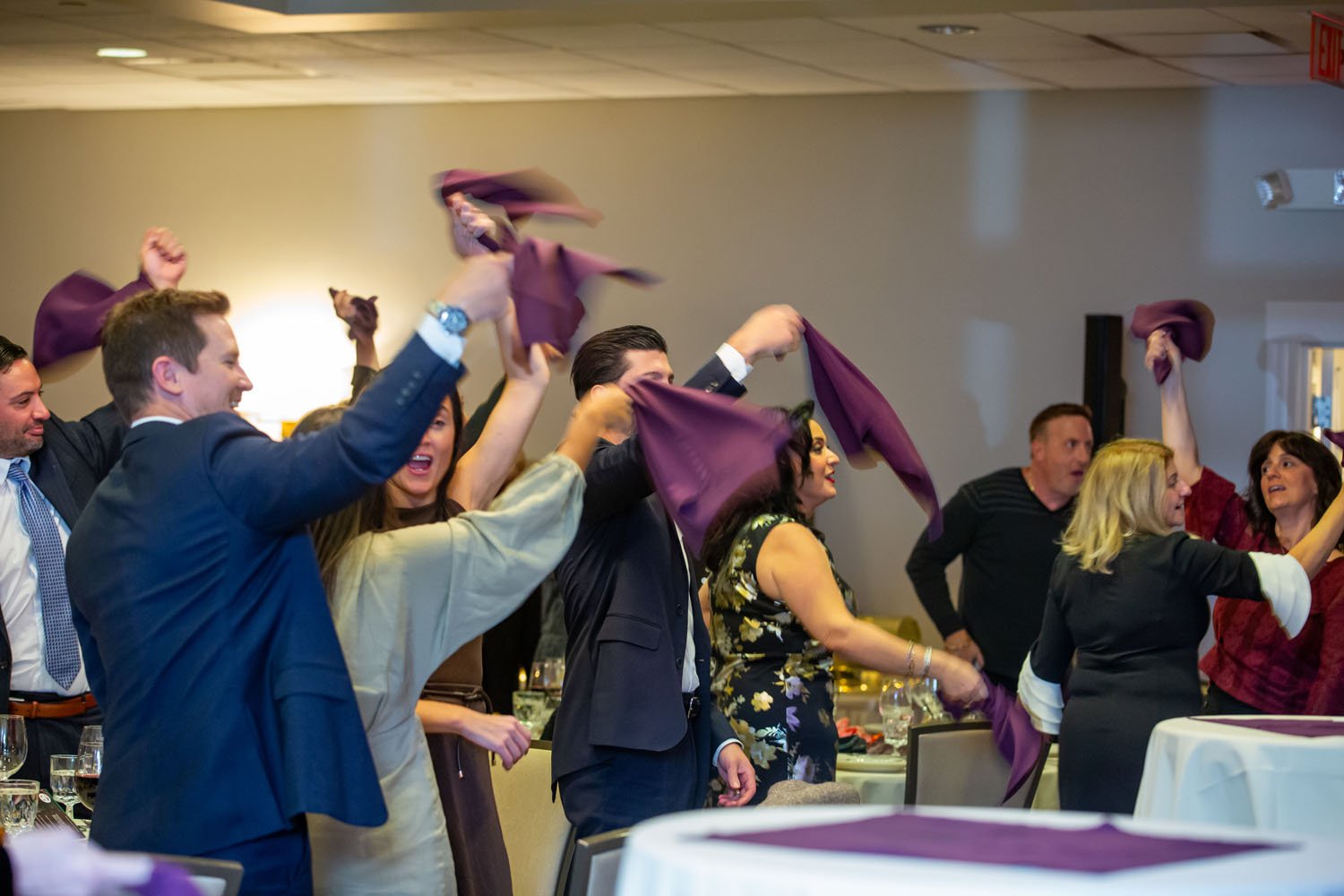 People celebrating at an indoor event, waving purple napkins