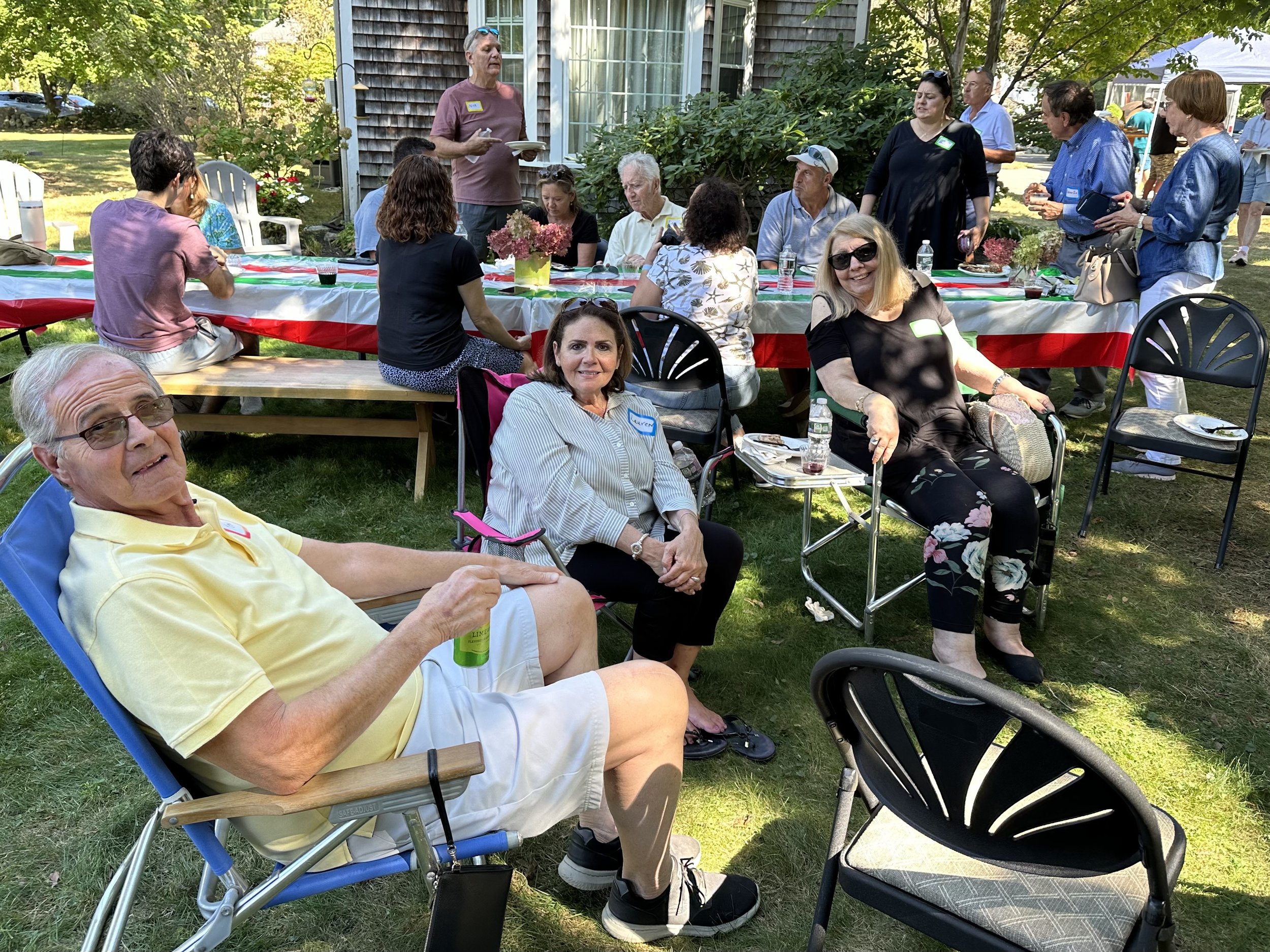 Group of people enjoying a garden party with food and drinks outdoors.