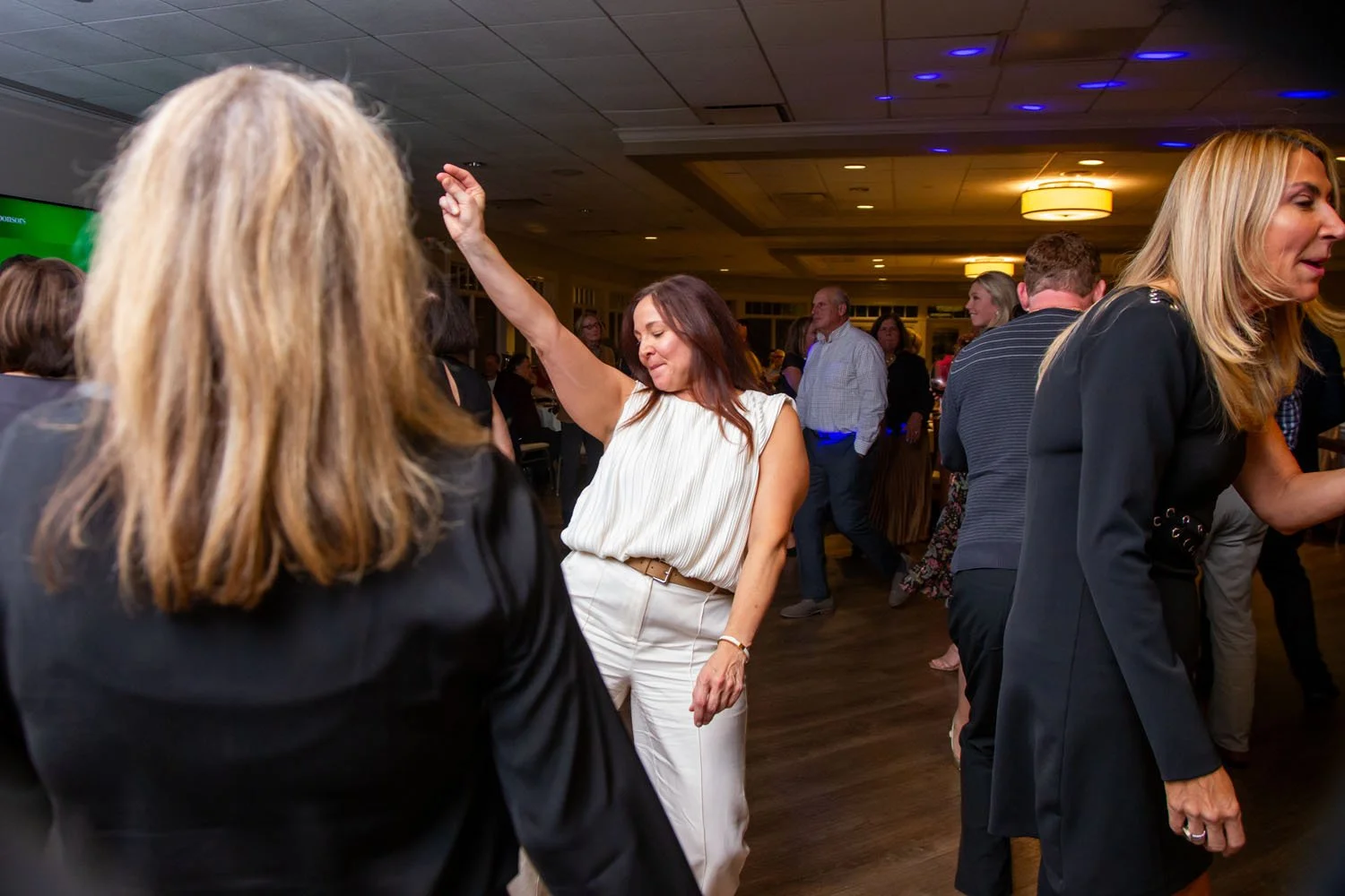 Group of people dancing at an indoor social event or party in a well-lit room.
