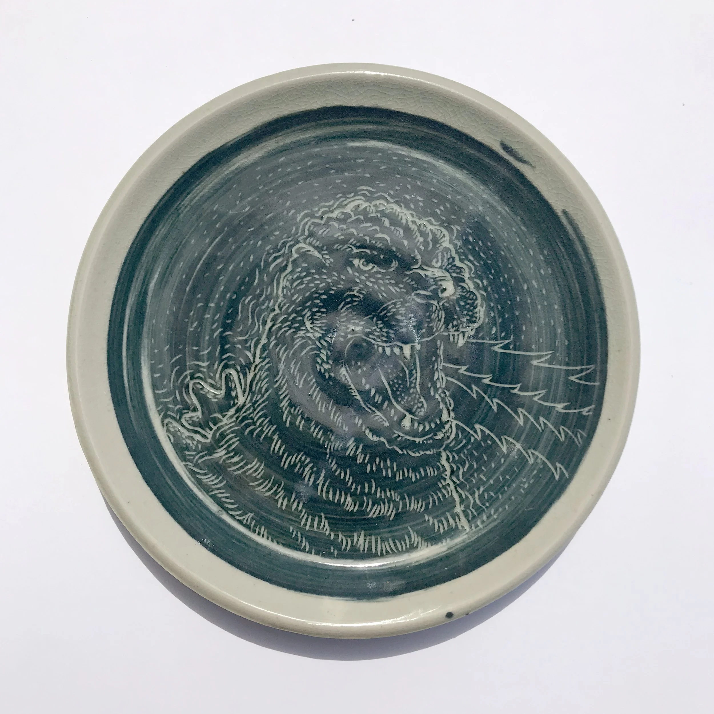 Ceramic plate thrown by Annette Roberts-Gray, sgraffito Godzilla added by Brian