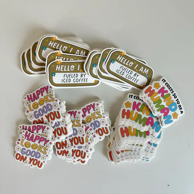 Stickers with cheerful messages: "Hello I am fueled by iced coffee," "Happy looks good on you," and "I cost to be kind human."