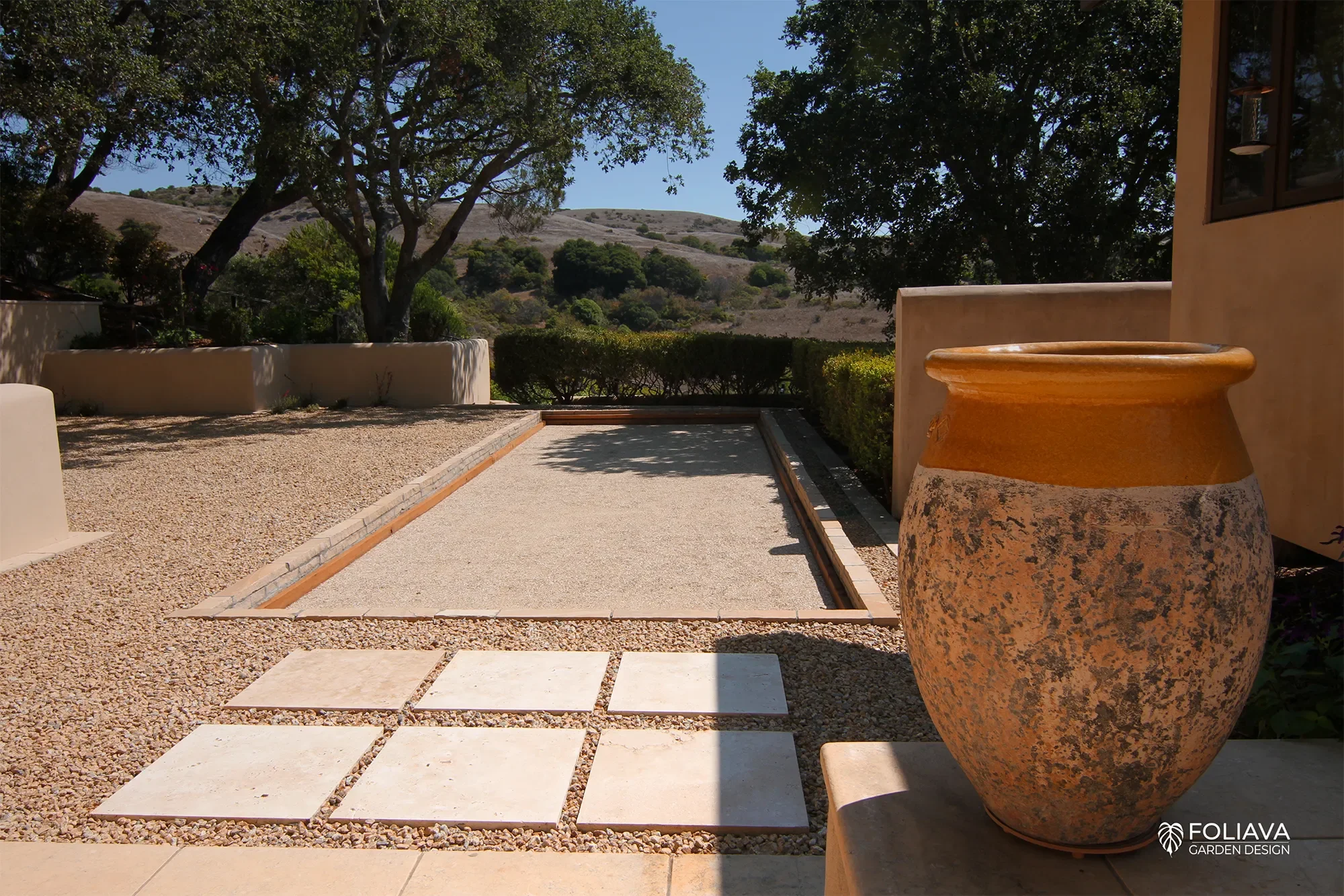 Elegant bocce court with stucco walls and olive trees, blending European charm with California living.
