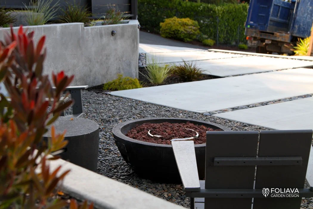 Outdoor fireplace in Corte Madera garden with modern pebble court and poured concrete