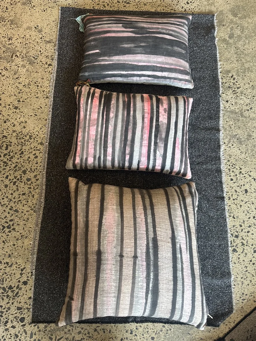 Three artist-striped lumbar linen cushions on a wool blanket.
