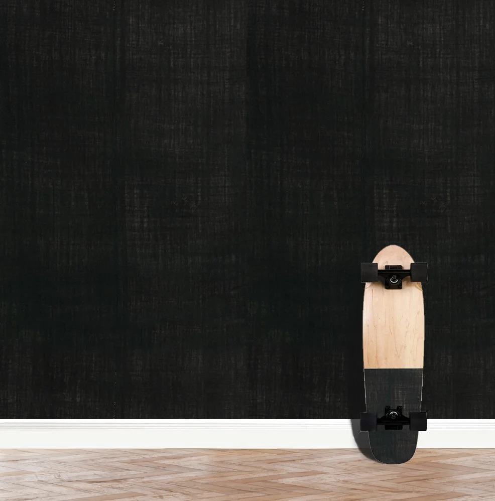 Indigo Yanbary wallpaper in a dark moody tone installed on a wall, with a skateboard leaning against the wall..