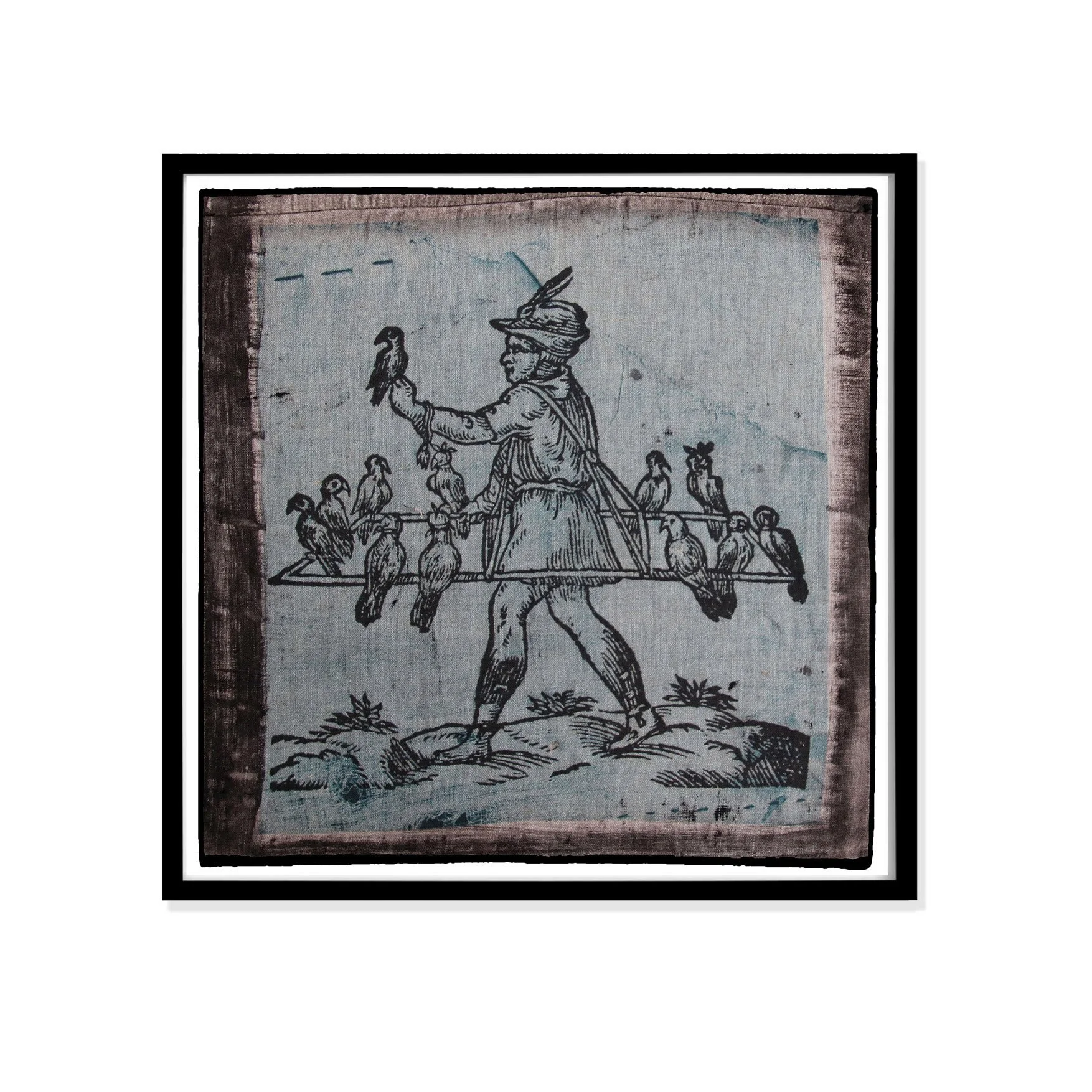 Illustration of birds by Claude Paradin with antique linen in a black frame against a white wall.