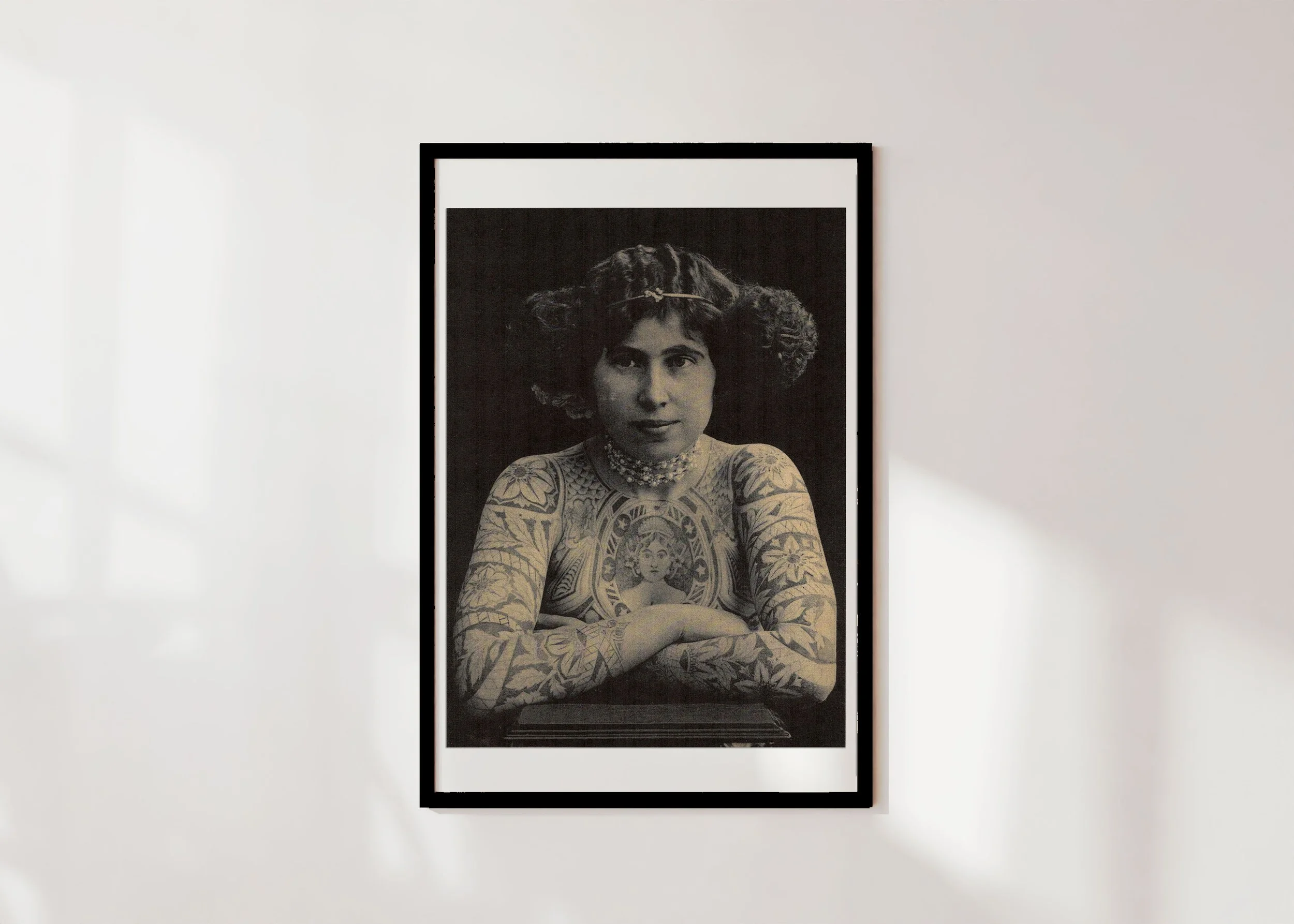 Framed print of vintage photograph of a woman's upper body covered in tattoos and with a pearl choker.