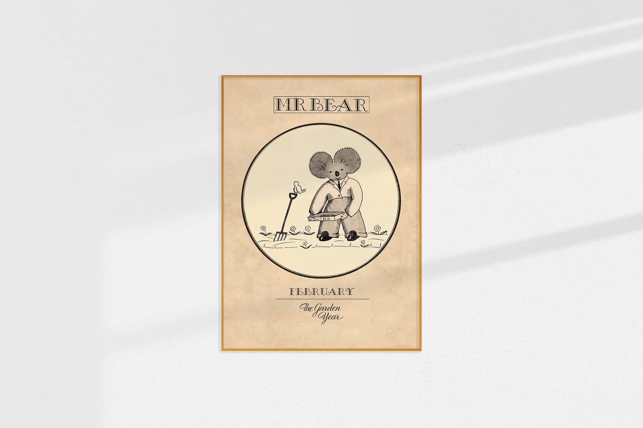 A framed Oz print with a koala Mr Bear in a roundel with a garden fork, a bird and a tray of bulbs.