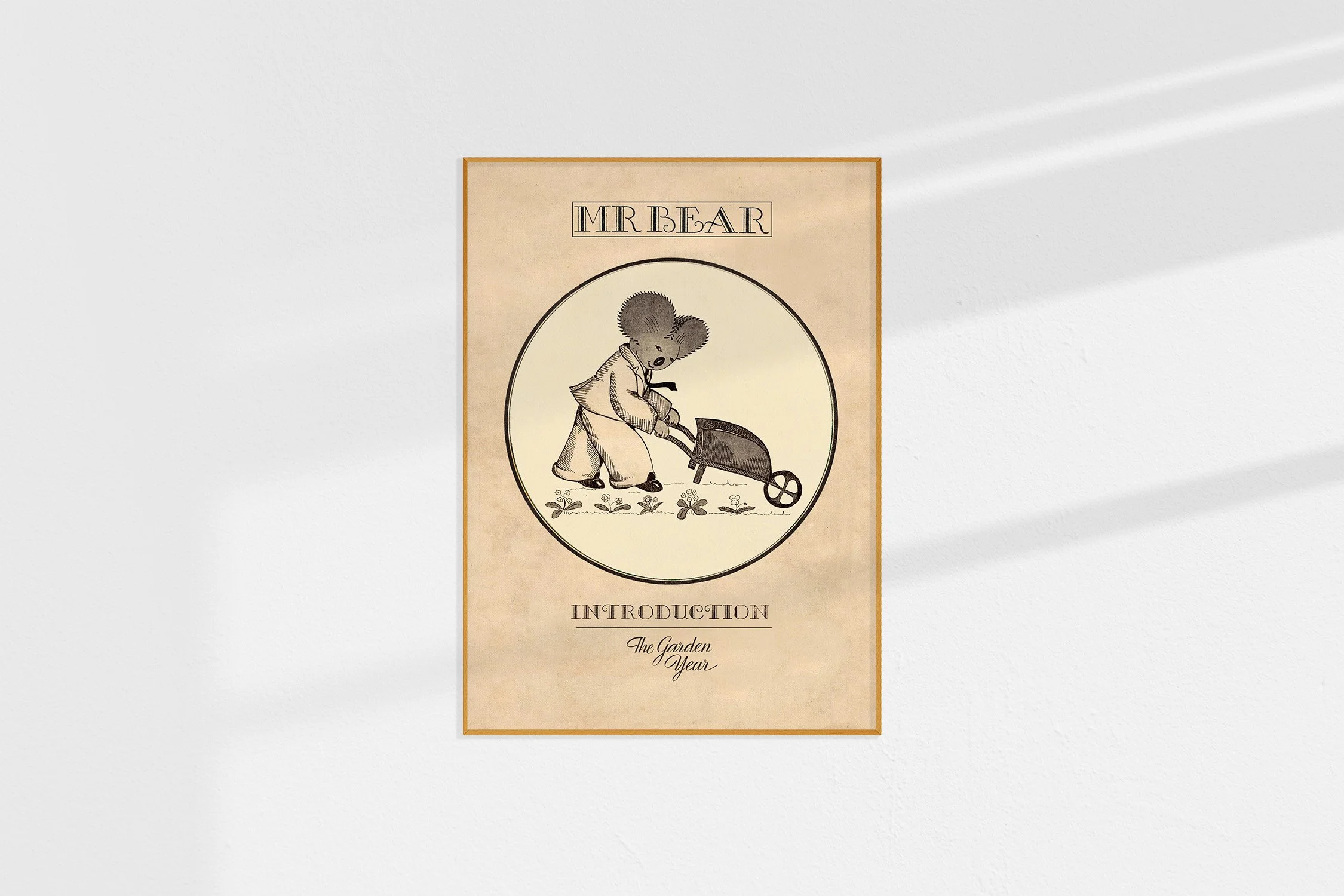 A framed Oz print with a koala Mr Bear in a roundel pushing a wheelbarrow.