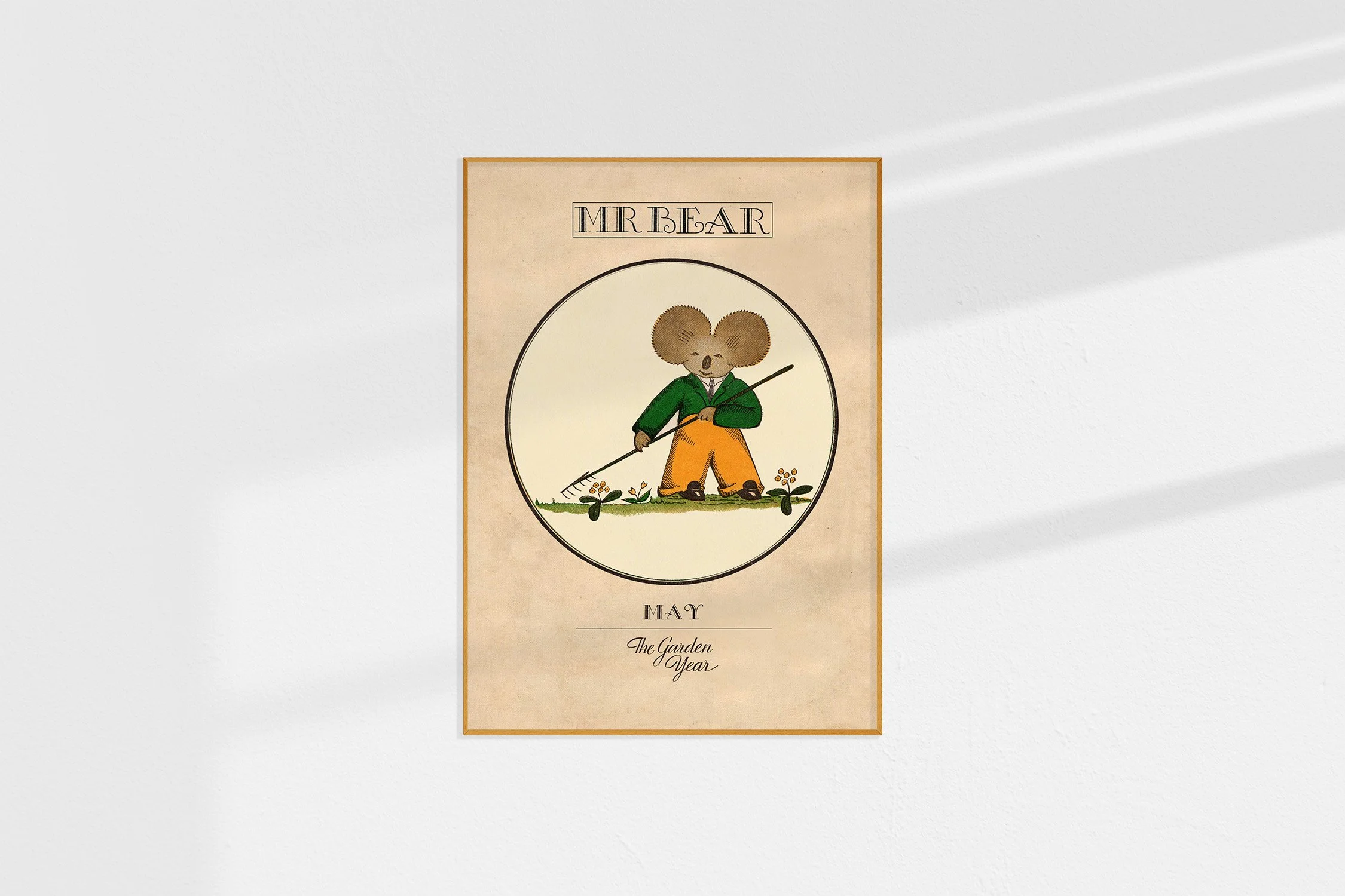 A framed Oz print with a koala Mr Bear in a roundel with a rake.
