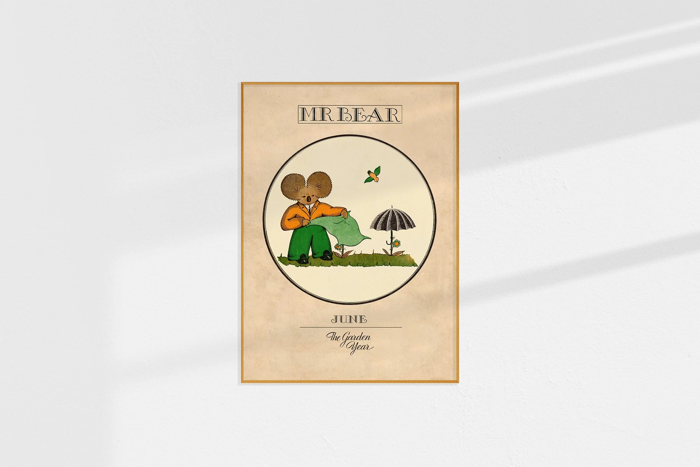 A framed Oz print of a koala Mr Bear in a roundel shading plants and with an umbrella.