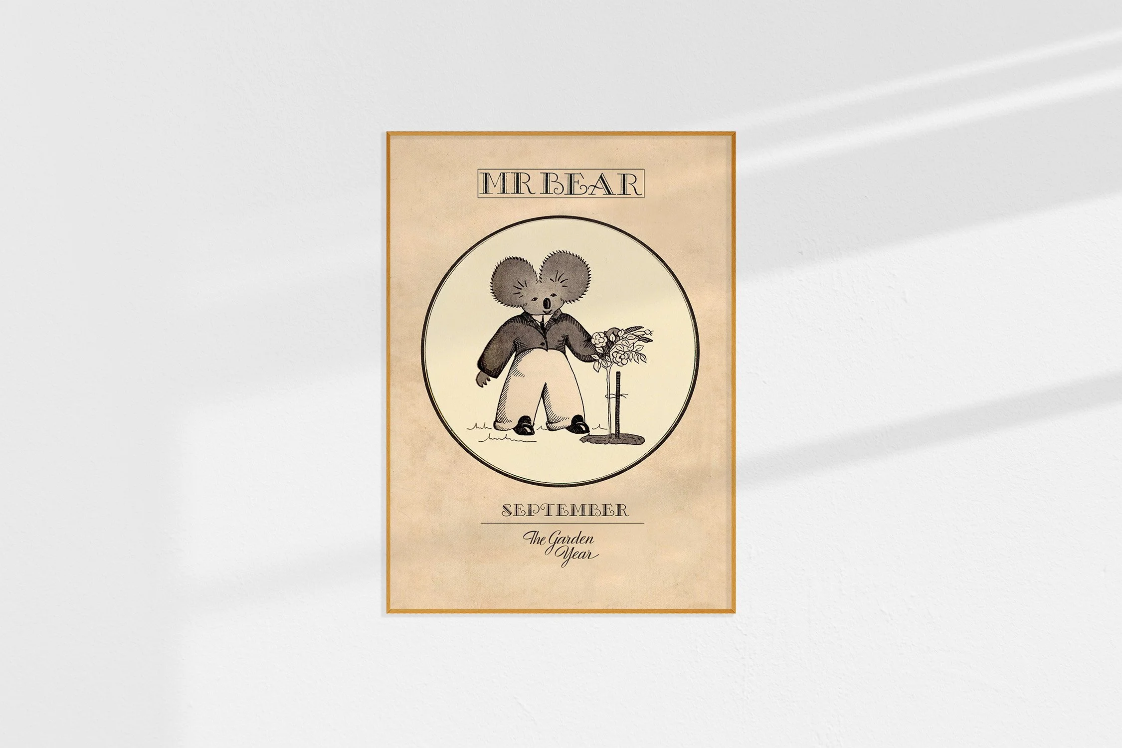 A framed Oz print with a koala Mr Bear in a roundel with roses.
