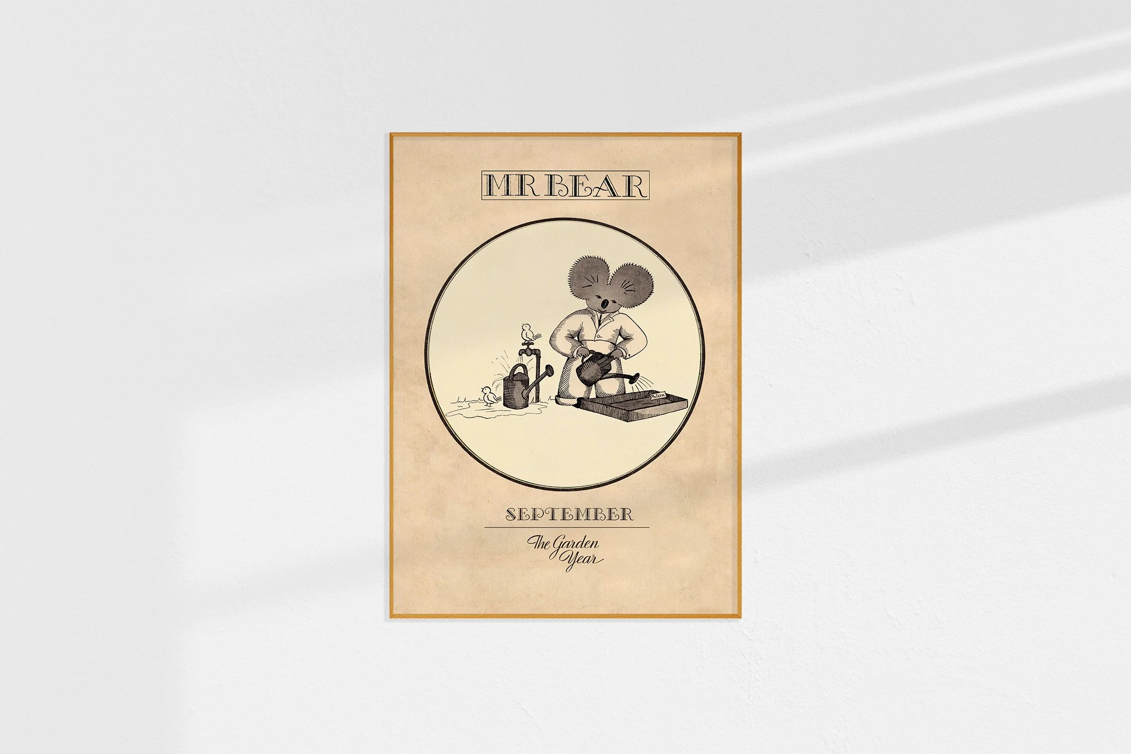 A framed Oz print of a koala Mr Bear and birds in a roundel with watering cans.