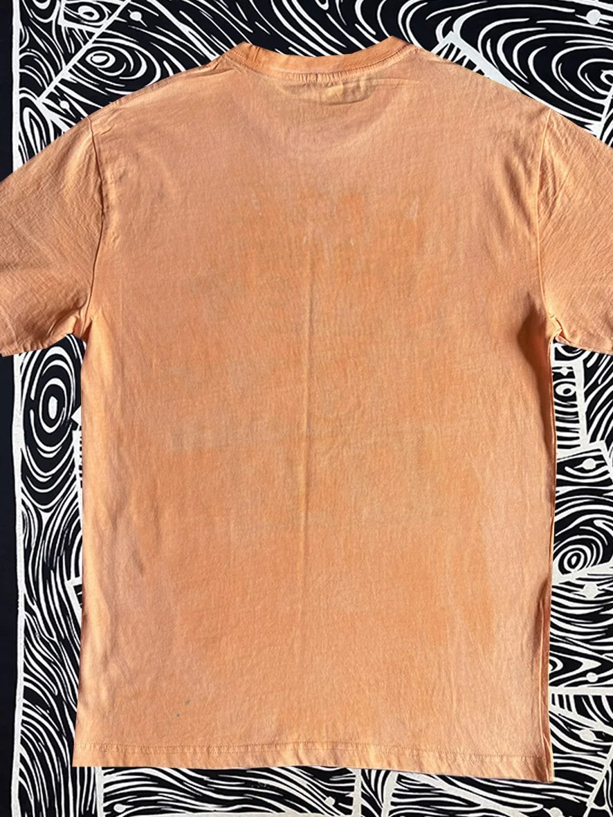 Back view of a treated orange tshirt with black and white woodgrain fabric behind.