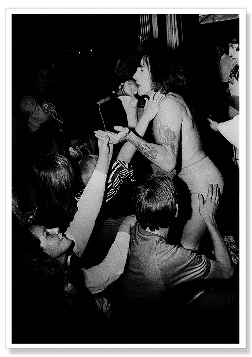 A black and white photographic portrait of a shirtless Bon Scott performing at Ormond House with adoring fans touching him.  Print shows borders and drop shadow.