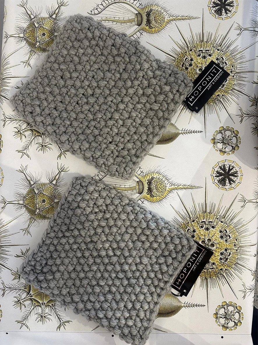 Two folded over knitted snoods (neck scarves) photographed on Haeckel wallpaper by Hoponit Studio.