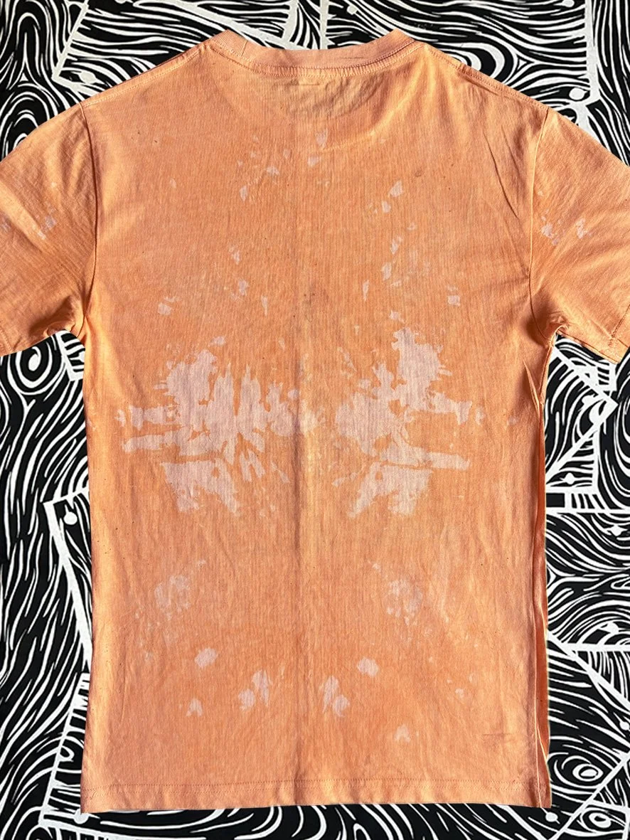 Back view of a treated orange tshirt and with black and white woodgrain fabric behind.