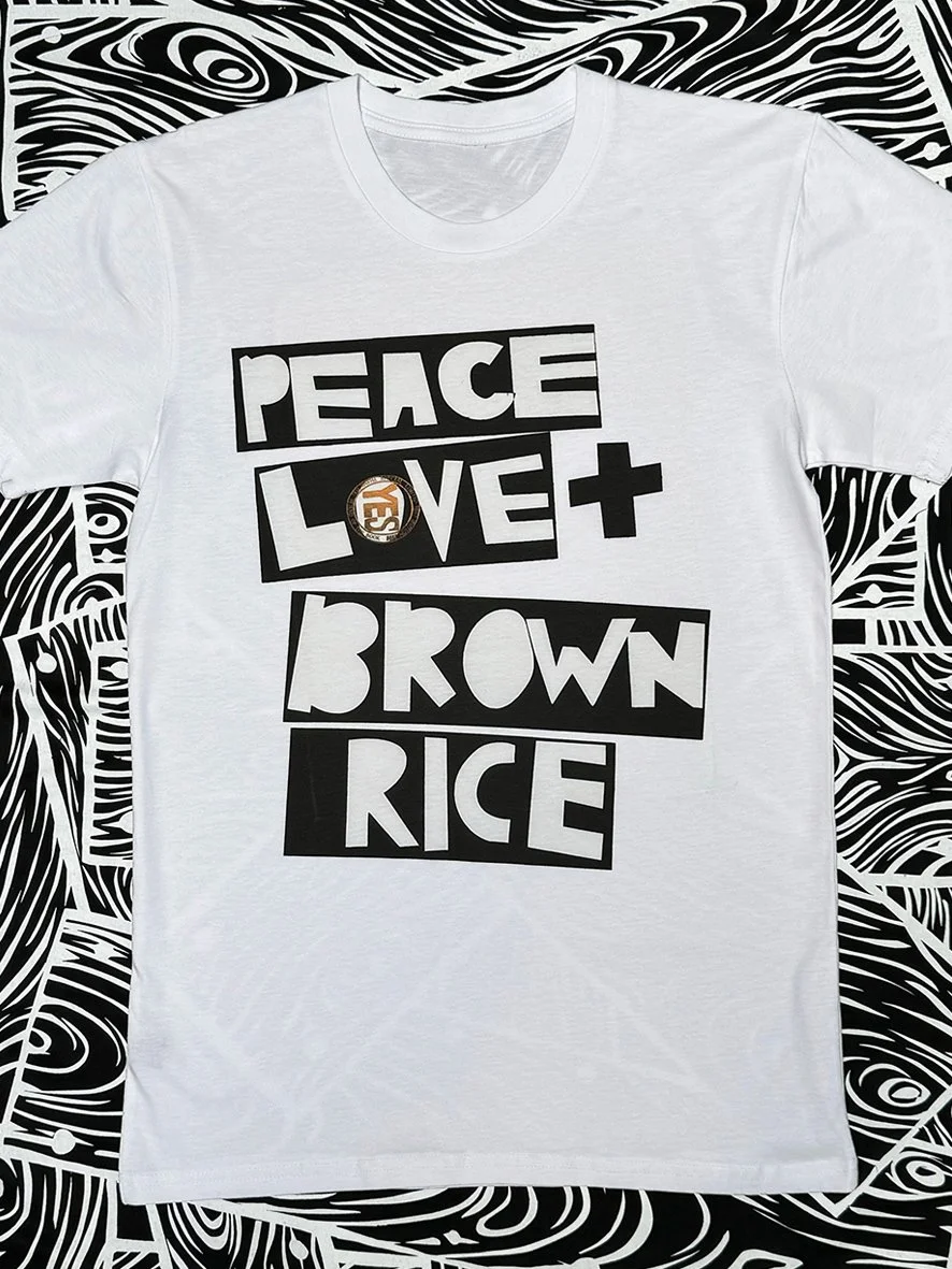 Front view of white short sleeved tee with a large Peace Love and Brown rice logo by Sophie Howarth.