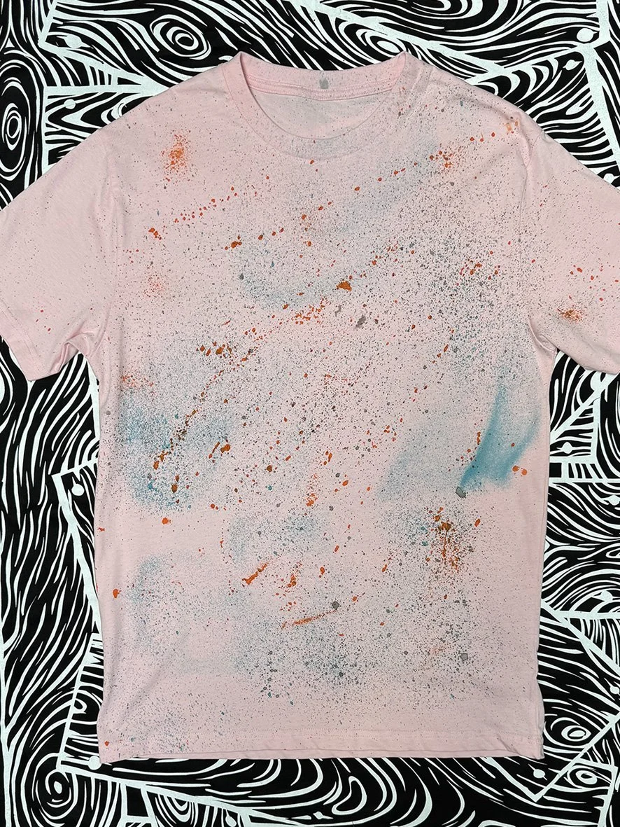 Front view of pink treated tshirt with black and white woodgrain fabric in the background.