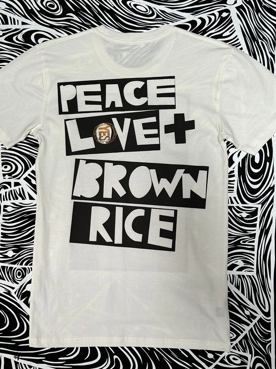 Back view of natural tee with a large Peace Love and Brown Rice logo print.