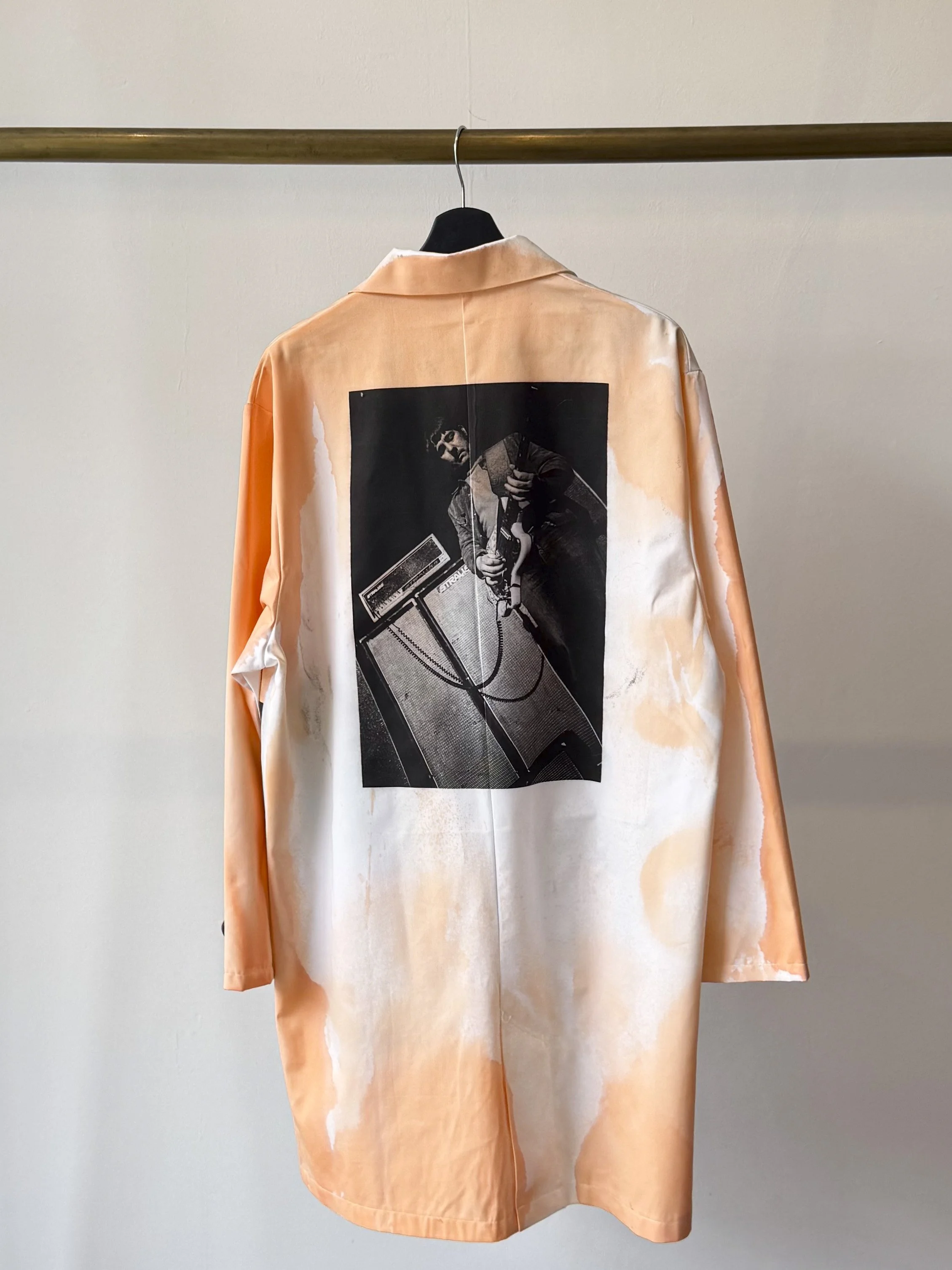 Back view of lab coat with artistic treatment in orange and featuring image of Lobby Loyde playing electric guitar.