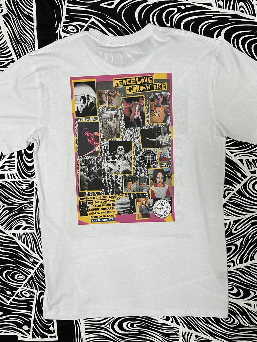 Back view of white tee with a large poster of an exhibition of Peace Love and Brown Rice and Colin Beard images.
