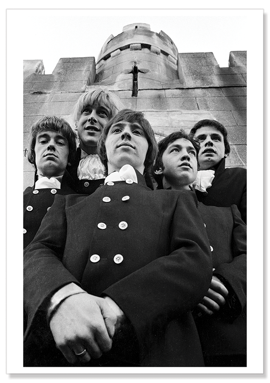 Black and white photograph of the Easybeats wearing double breasted dark suits and white scarves against a castle backdrop.  Print shows borders and drop shadow.