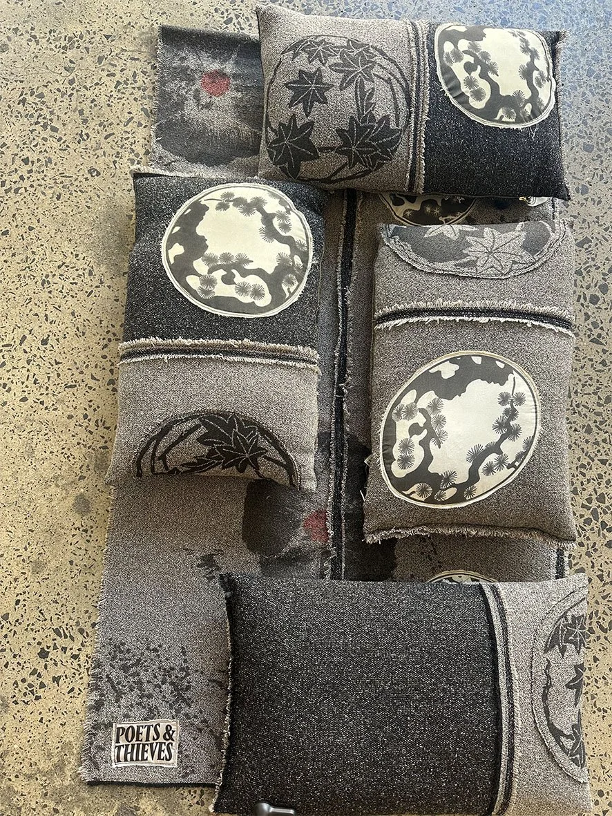 Sakura wool and silk cushions styled together with a poppy woollen scarf on a concrete floor..