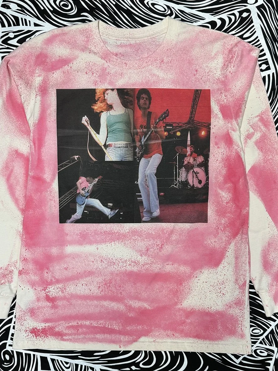 Front view of Peace Love and Brown Rice image of performers by Sophie Howarth on a long sleeved natural tee with oxidised treatment in pink.